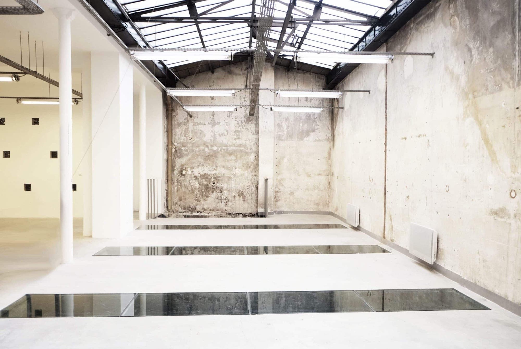 Empty industrial event space with skylight and concrete walls.
