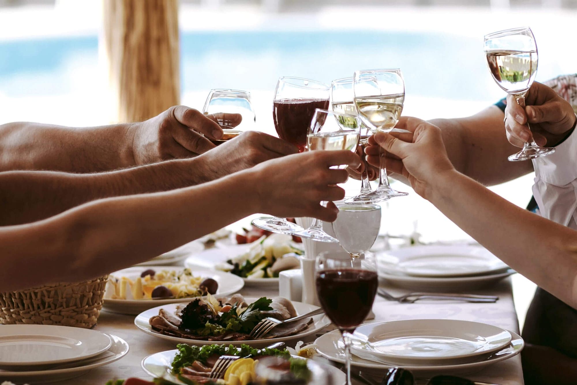 People toasting with wine glasses at a table set for a meal.