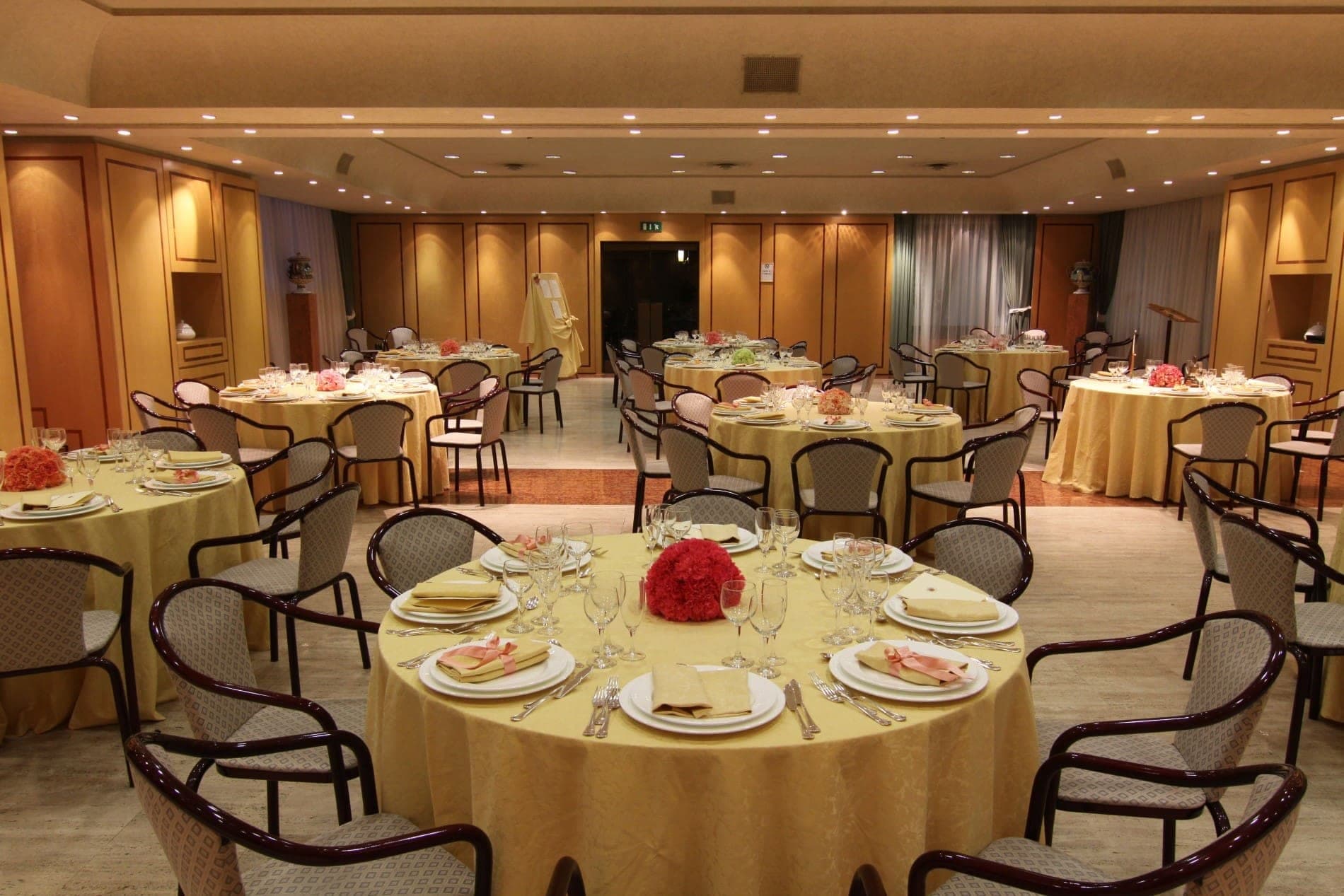 A reception room with round tables set for a wedding.