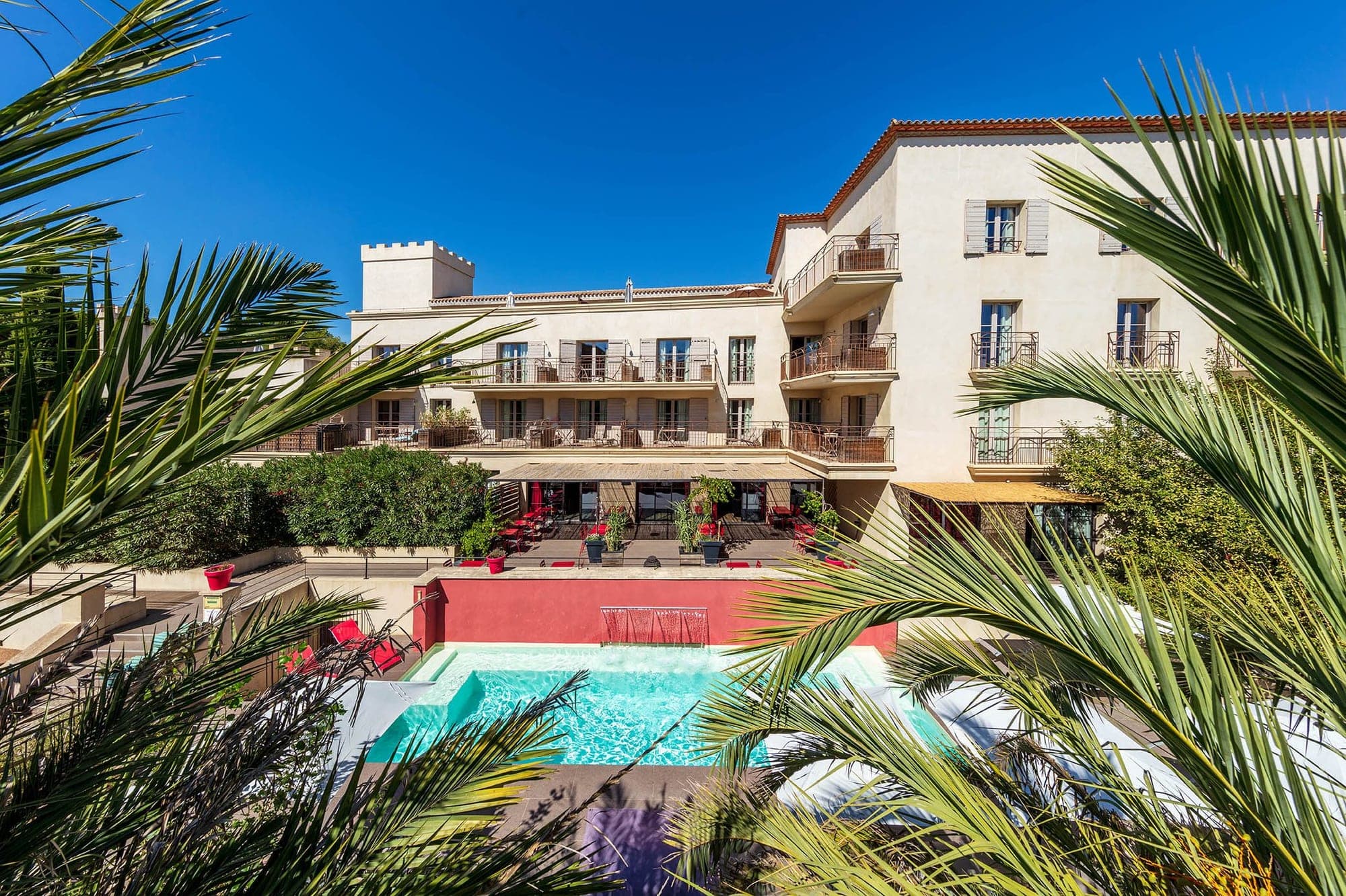 Exterior of a hotel with a pool and palm trees