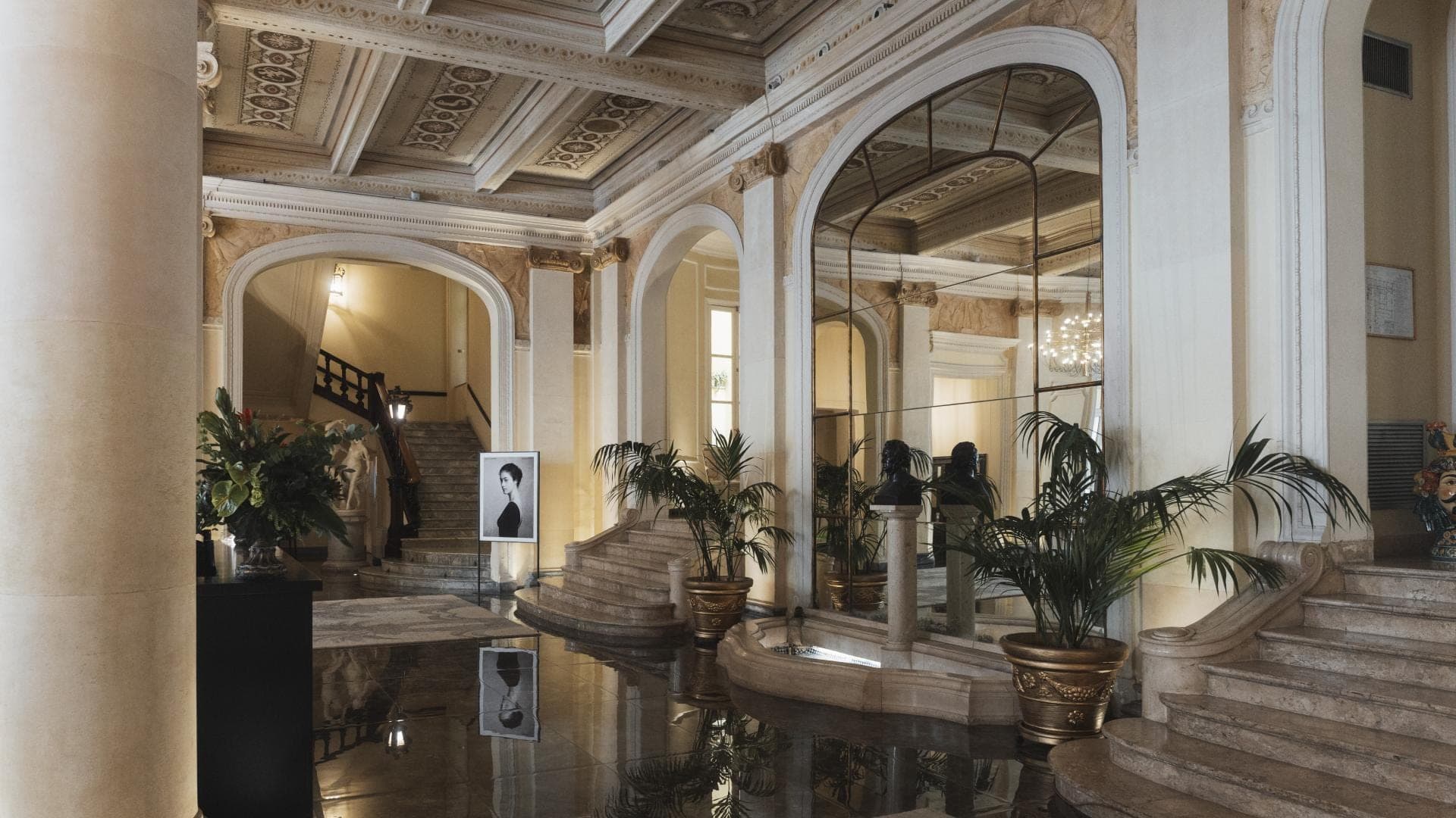 Interior of a hotel lobby with a grand staircase and fountain.