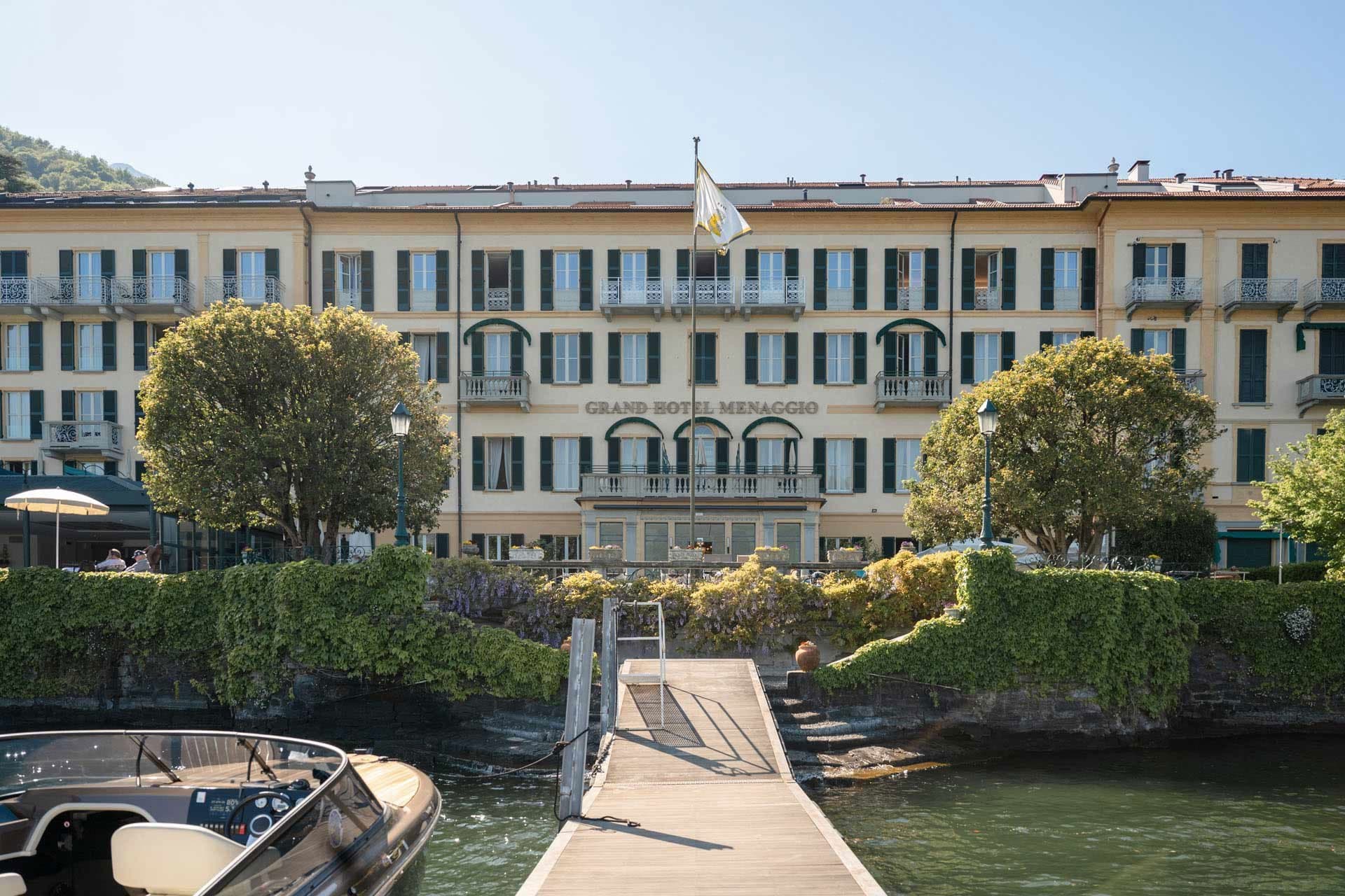 Grand Hotel Menaggio building facade with a dock and water in front.