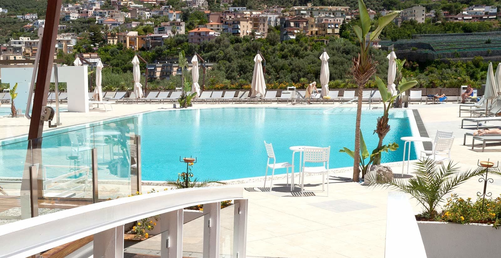 Swimming pool area with lounge chairs and town view.