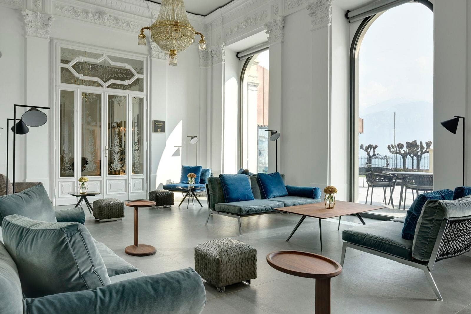 Lounge area with blue sofas and a view of a lake through large windows.