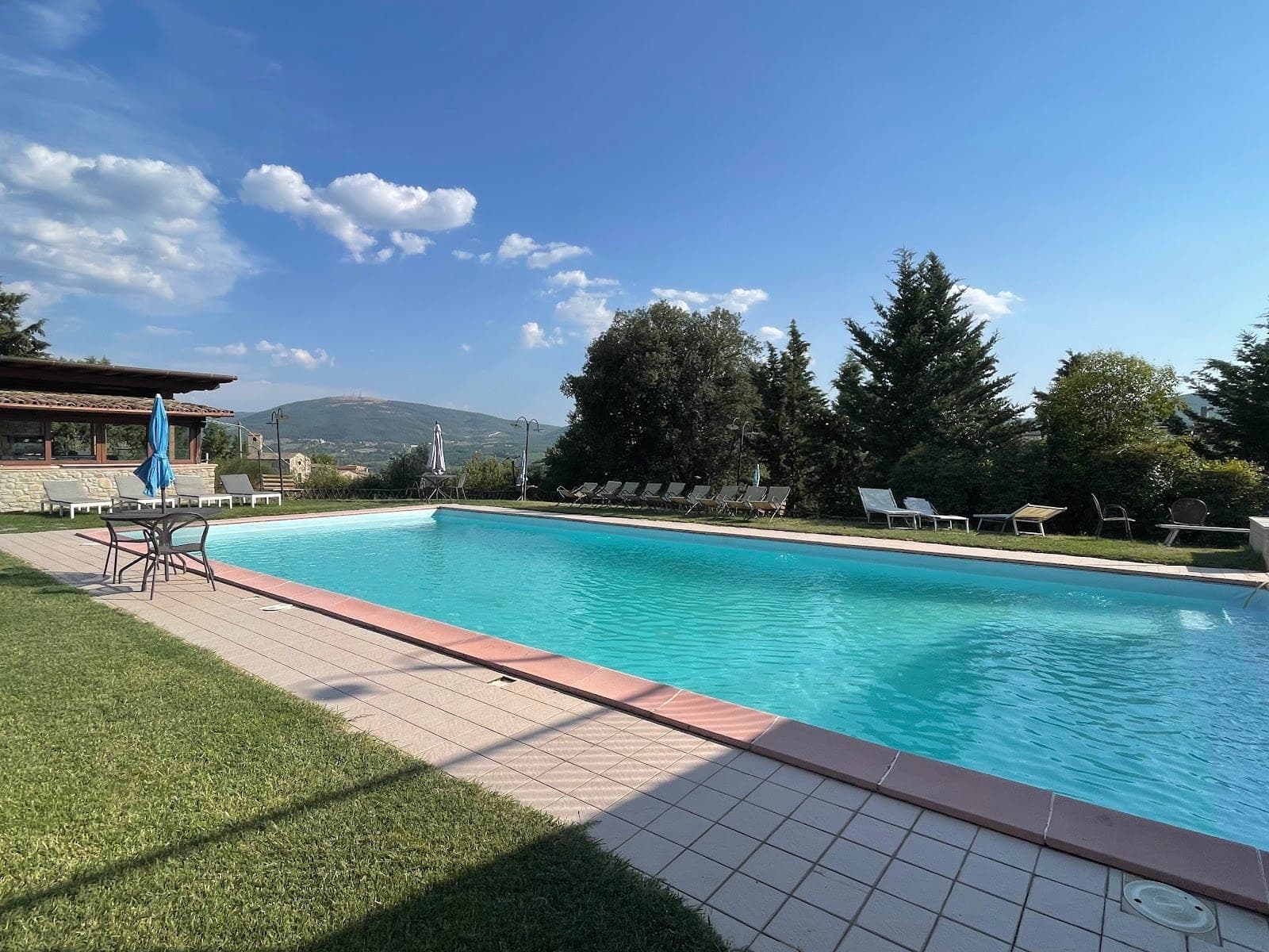 A swimming pool with lounge chairs and tables on the grounds of a venue.