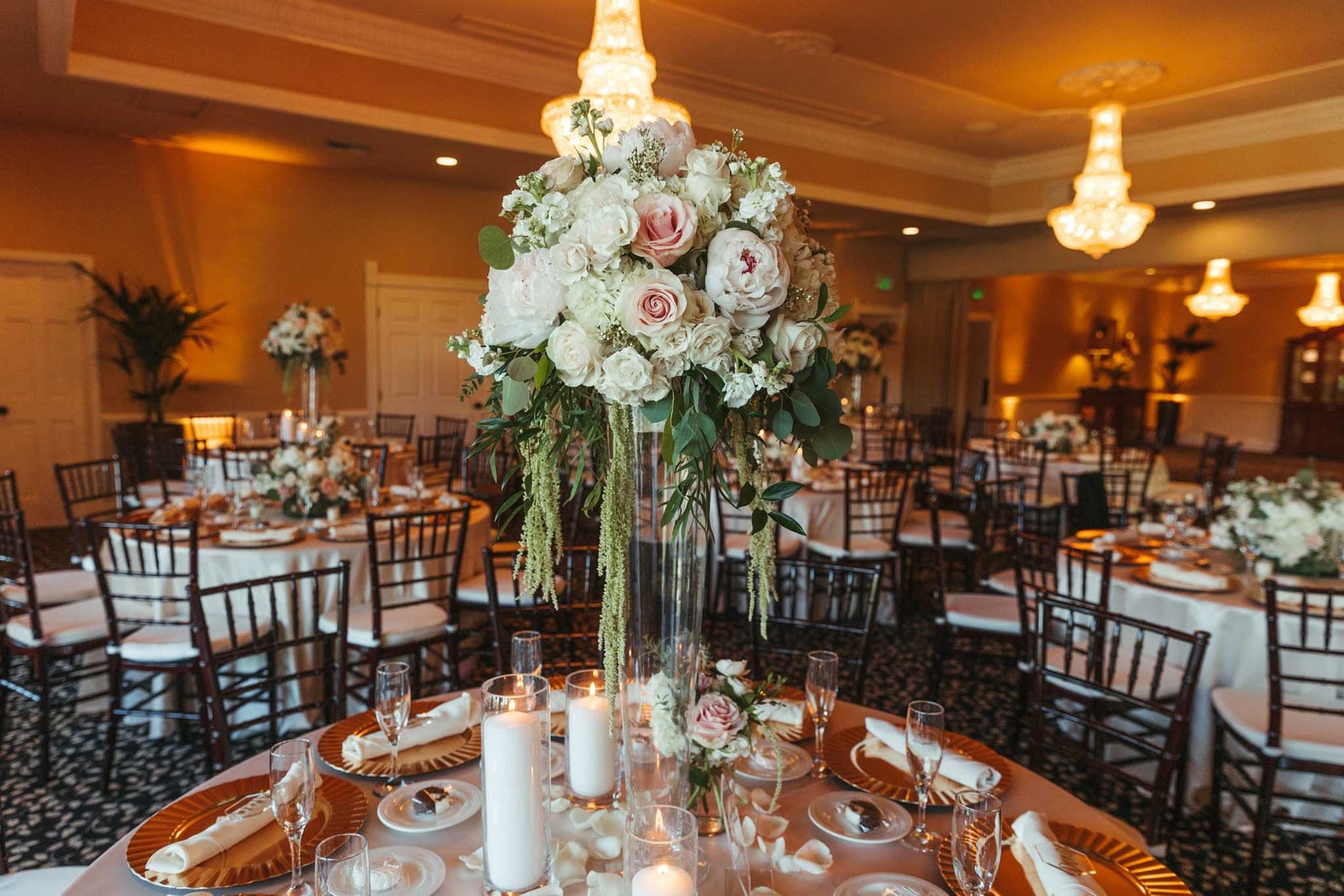 A reception hall with round tables set for a wedding feast.