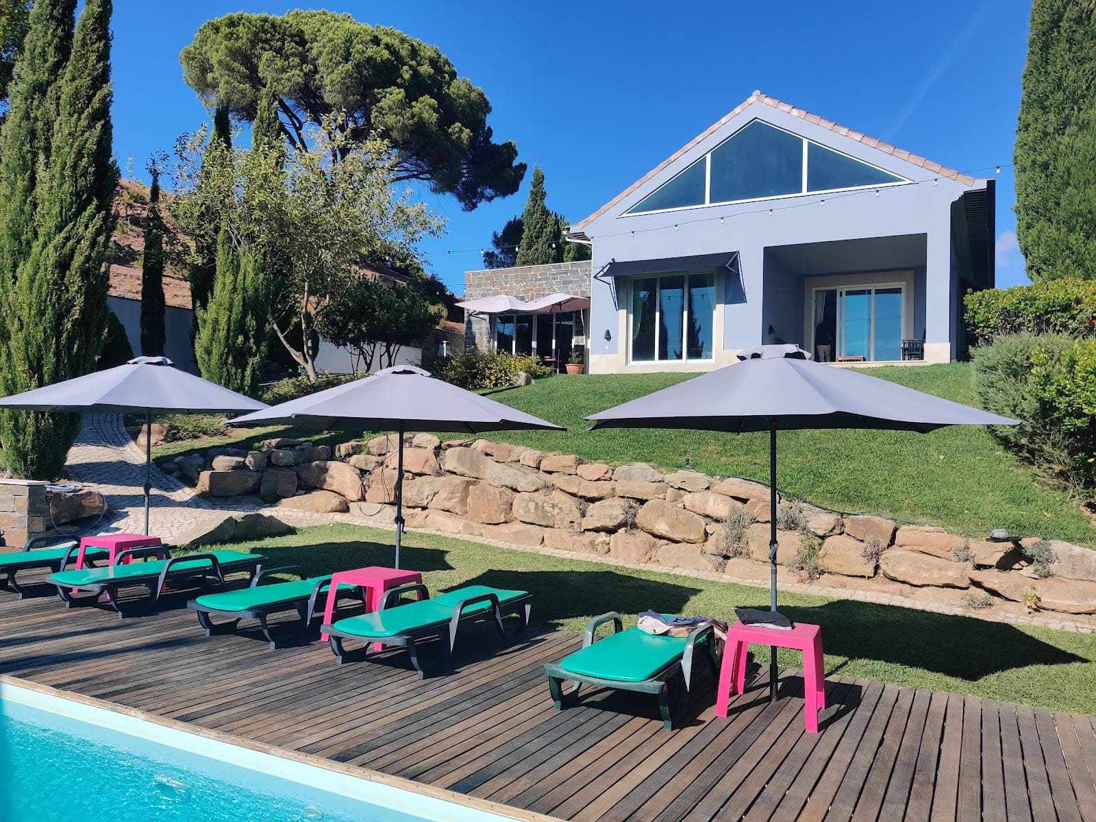 Swimming pool area with lounge chairs and umbrellas in front of a building.