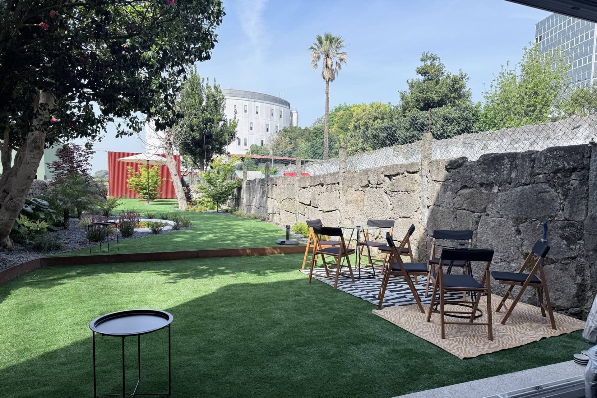 A garden with artificial grass, seating, and a stone wall.