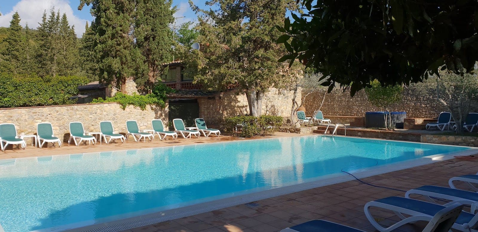 A swimming pool with loungers and trees at a venue.