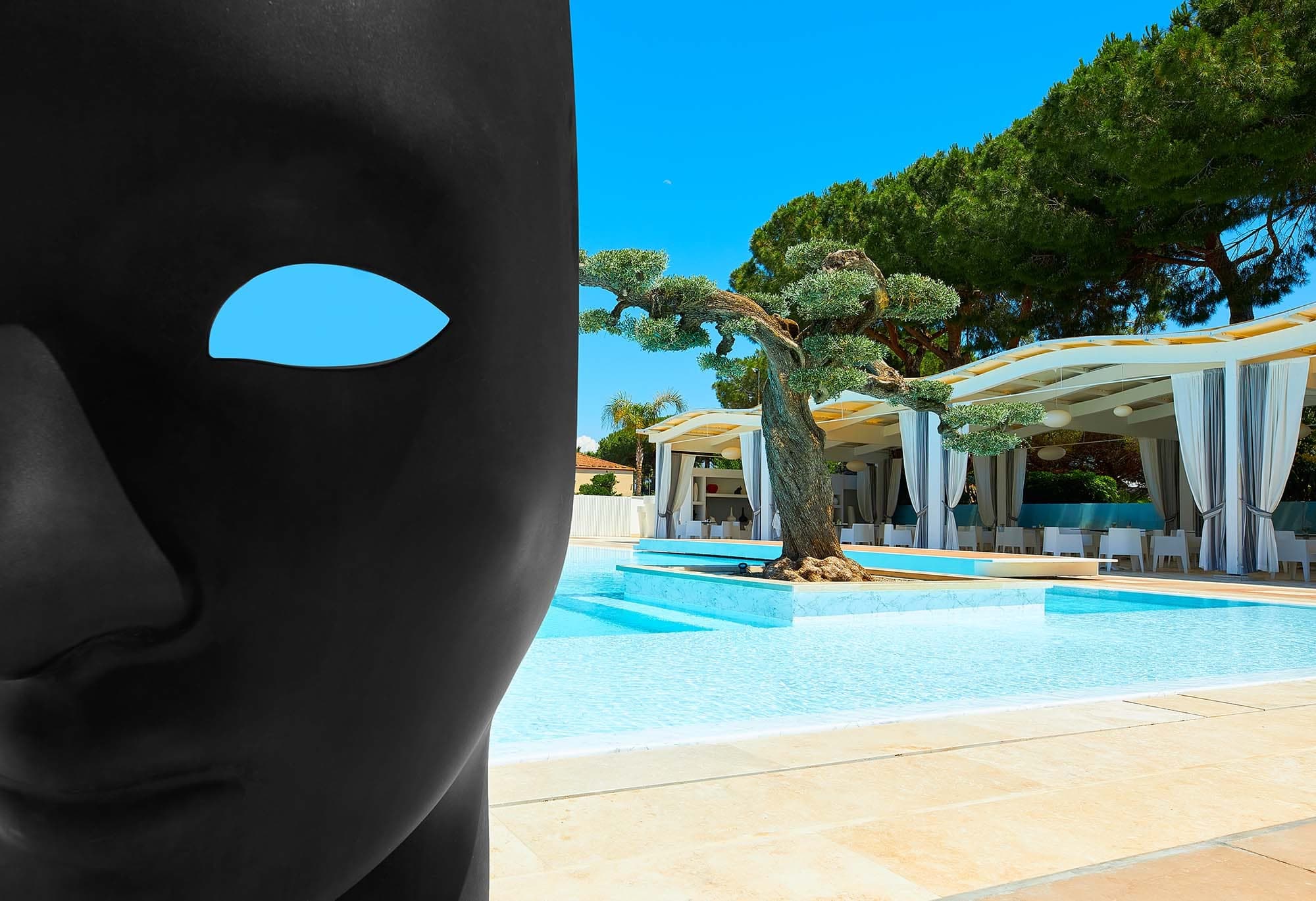 A swimming pool area with cabanas and trees, partially obscured by a black mask.