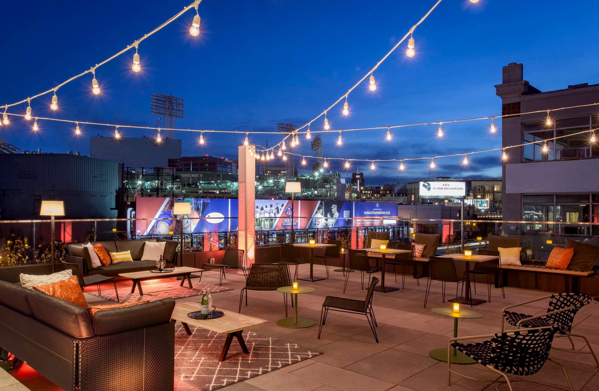 Rooftop terrace with seating and string lights at dusk.