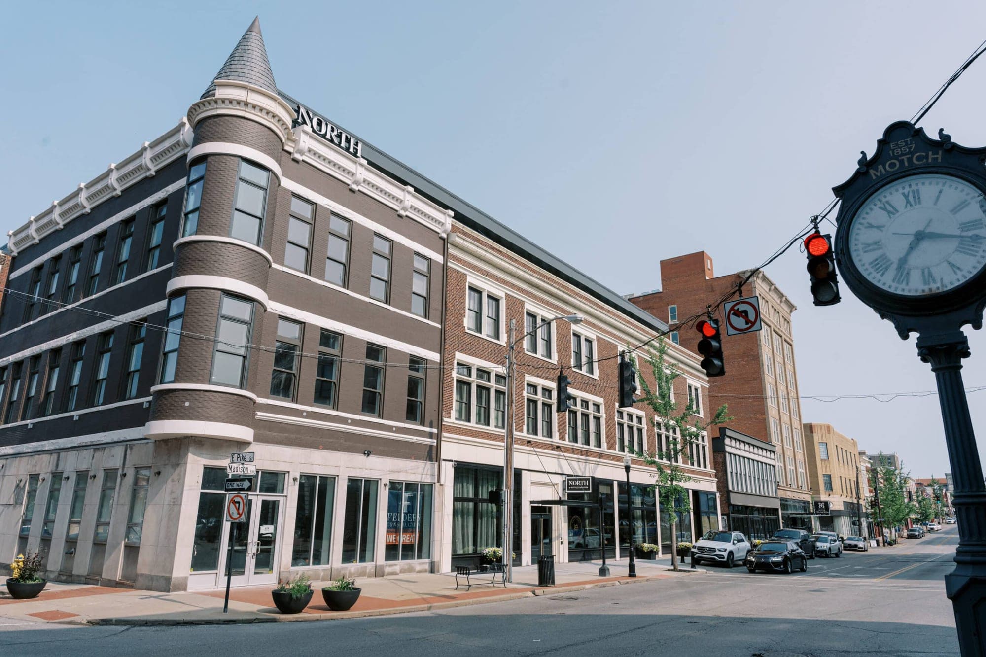 Exterior of a multi-story brick building with a rounded corner and a spire.