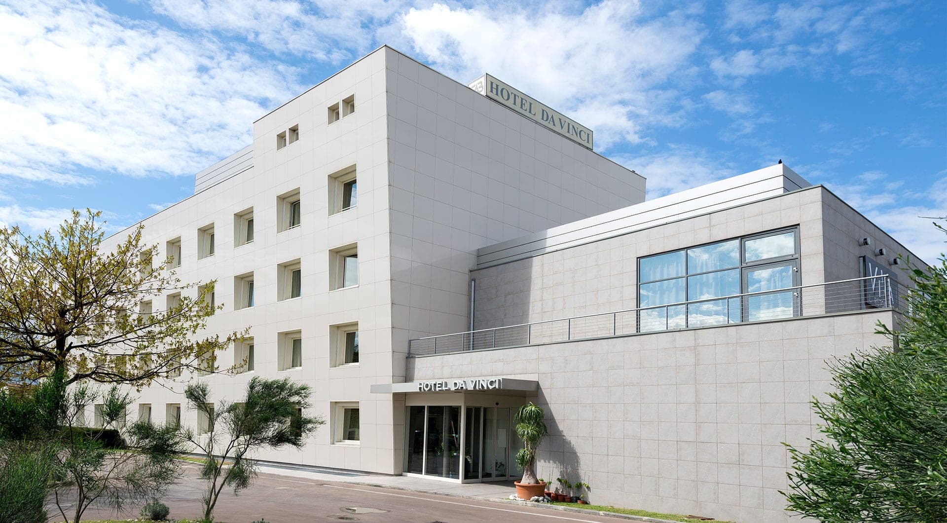 Exterior of the Hotel da Vinci building with a blue sky and clouds.