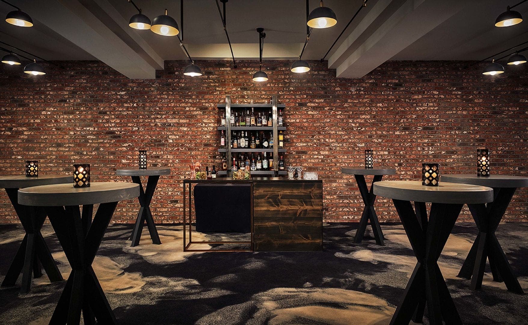 A bar area with high-top tables and a brick wall.