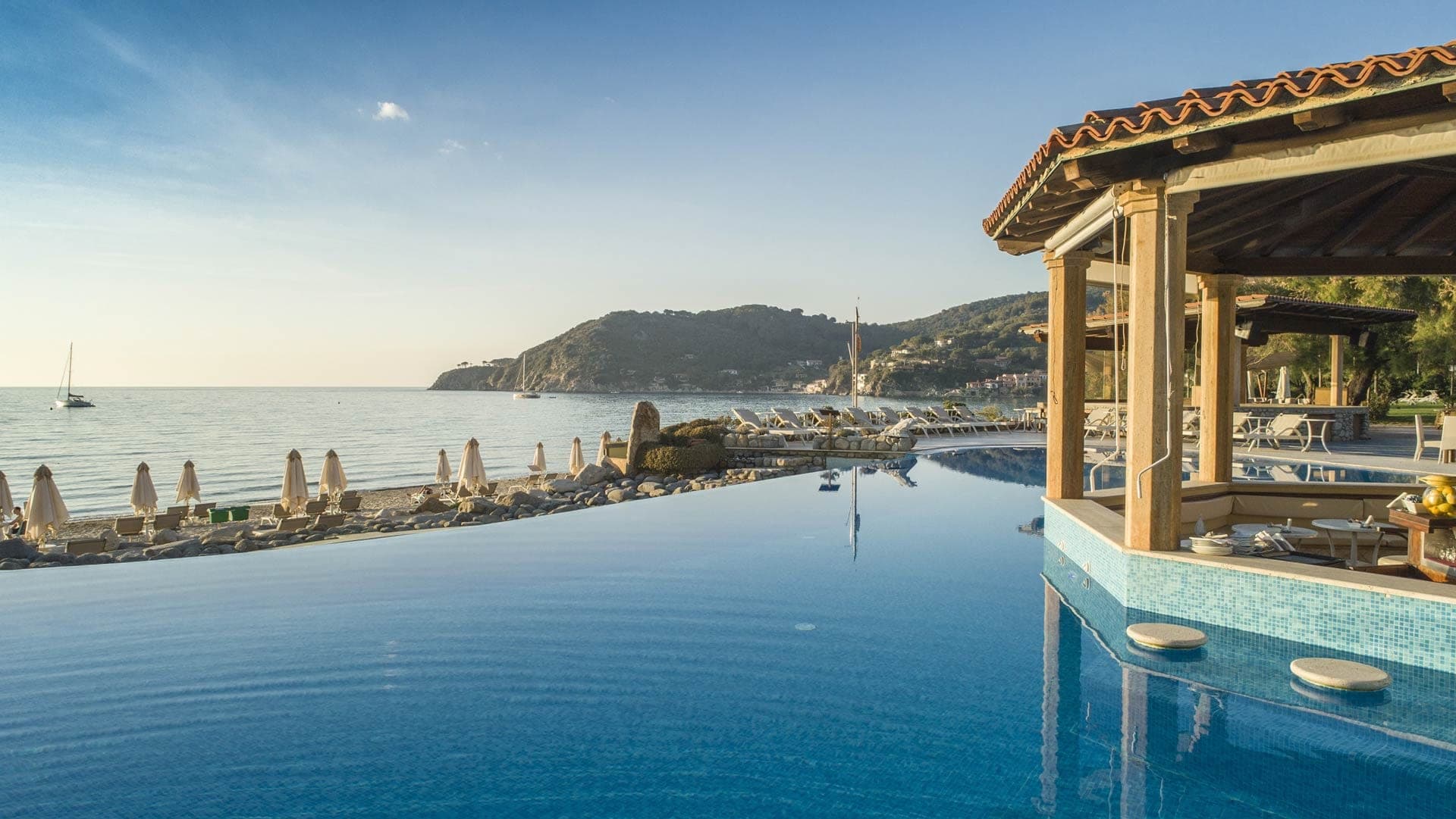 Infinity pool and bar area overlooking the sea and hills.