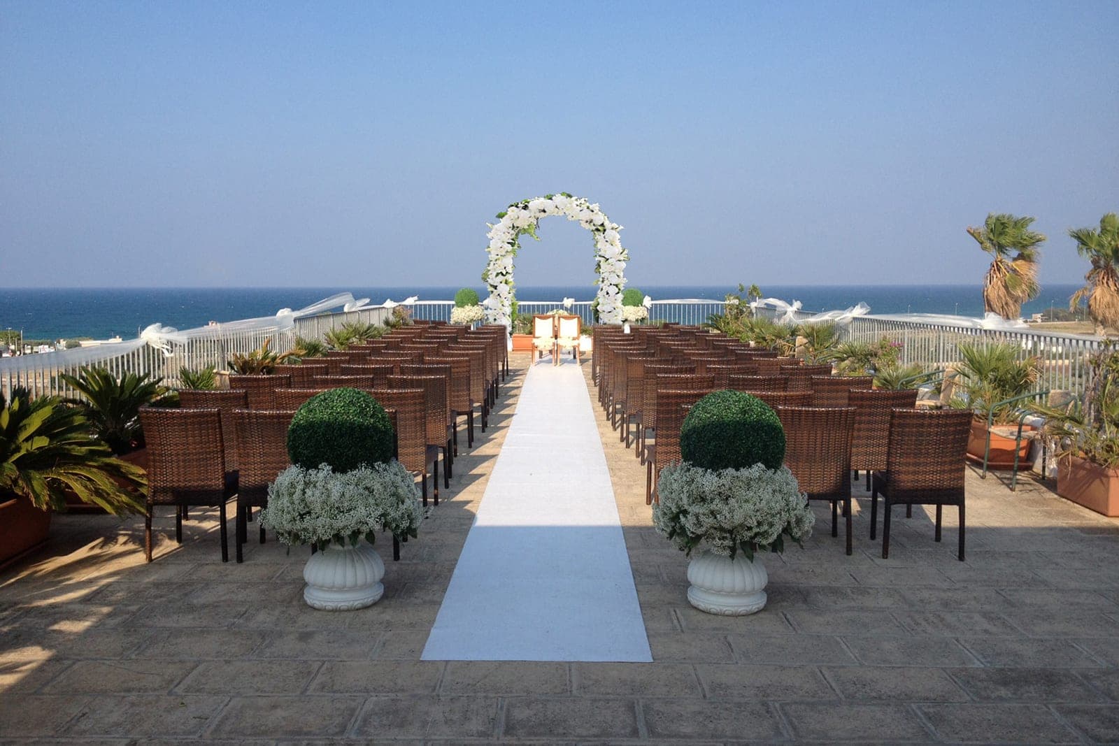Wedding ceremony setup with chairs and floral arch overlooking the sea.