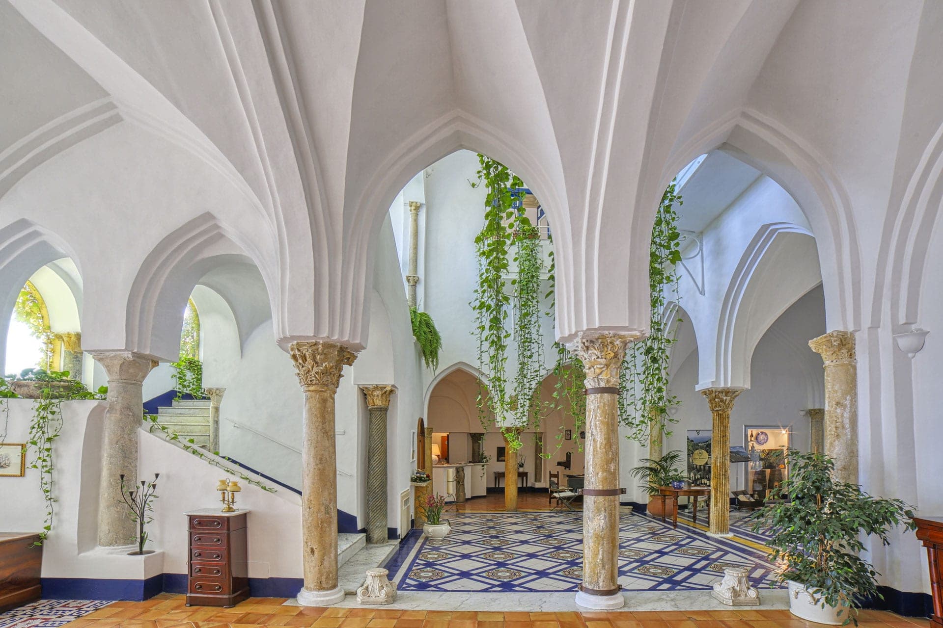 Interior courtyard with arches, columns, and hanging plants.