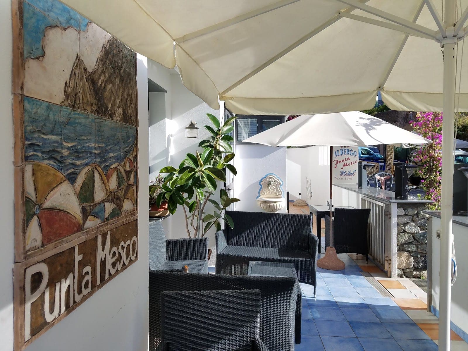 Outdoor seating area with umbrellas and a mural of the sea and mountains.