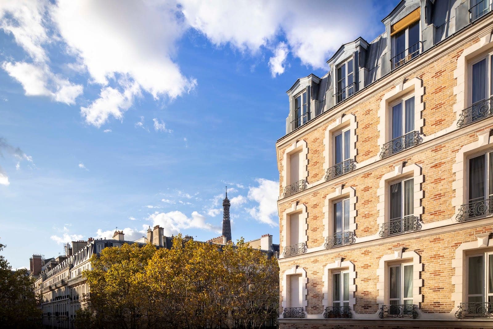 Exterior of a Parisian building with the Eiffel Tower visible in the distance.