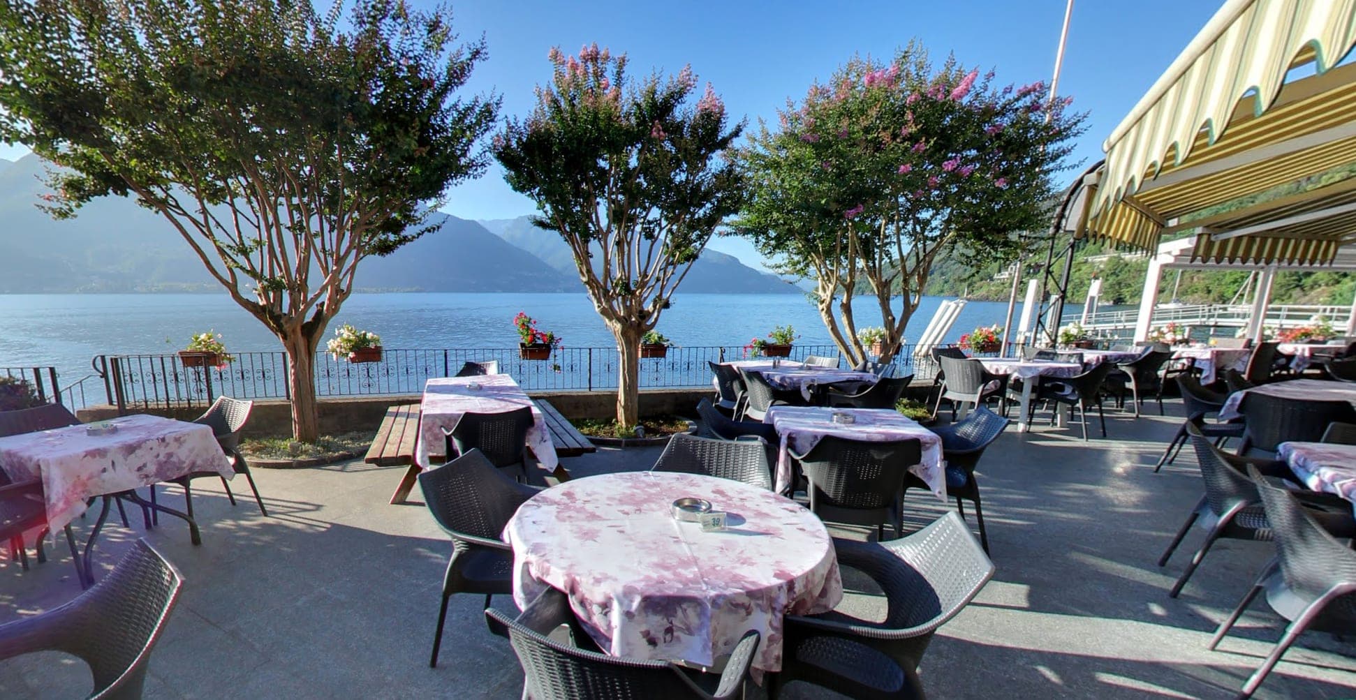 Terrace with tables set for dining overlooking a lake and mountains