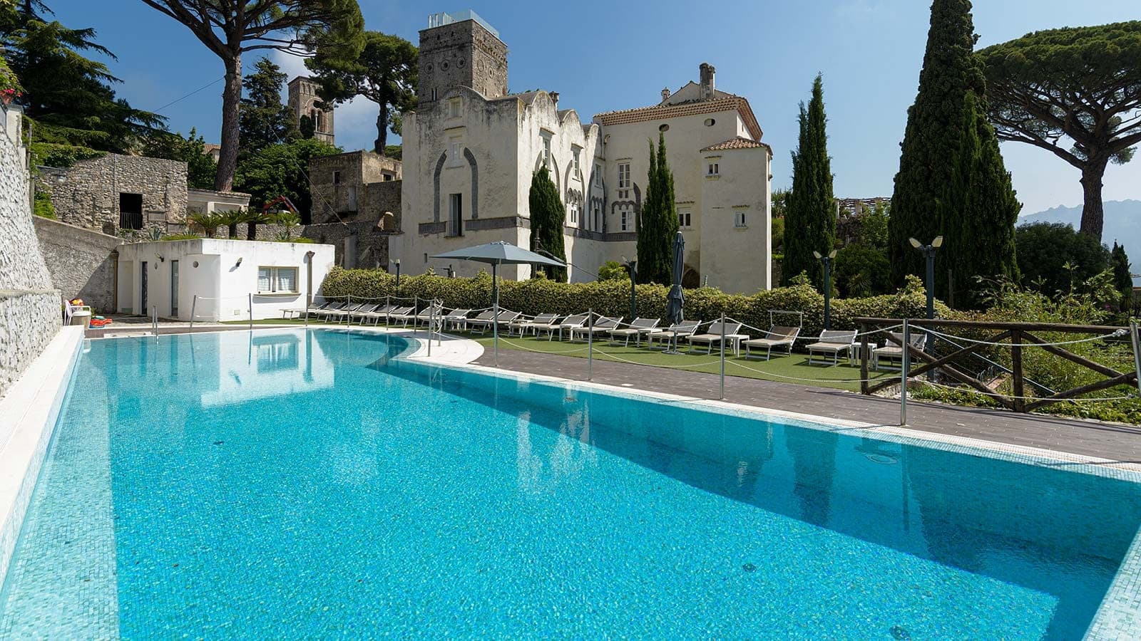 Swimming pool with loungers and a historic building in the background.