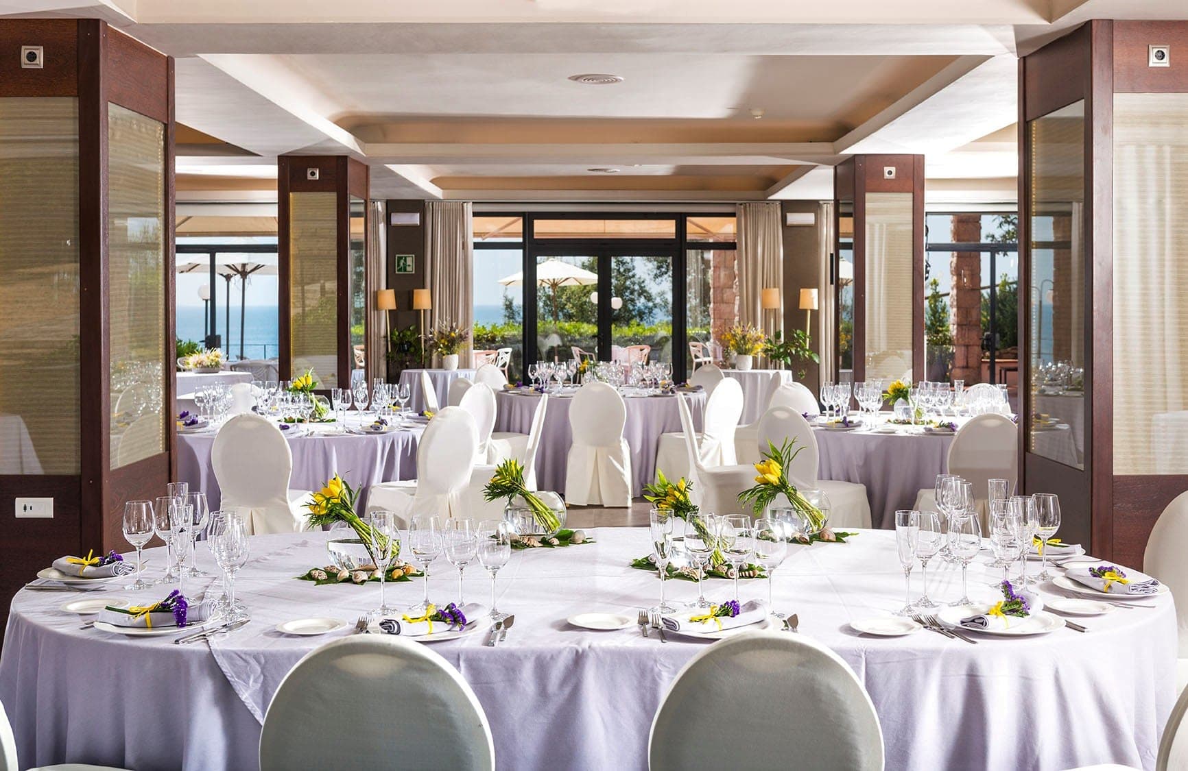 Wedding reception room with tables set for dinner and a sea view.