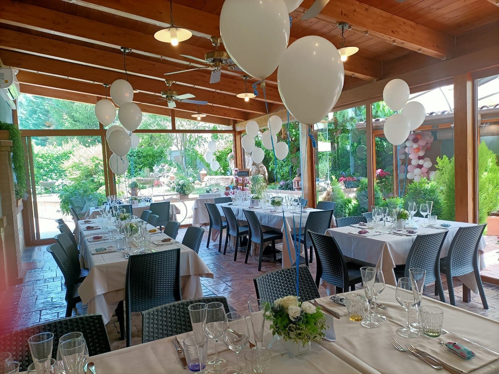 A reception room with tables set for a wedding, decorated with balloons.