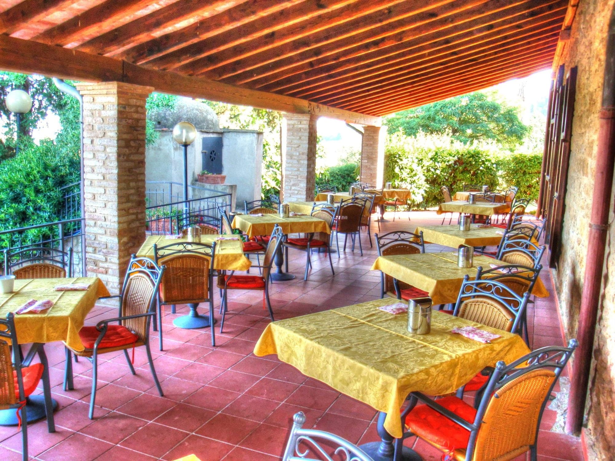 Covered outdoor dining area with tables set for guests.