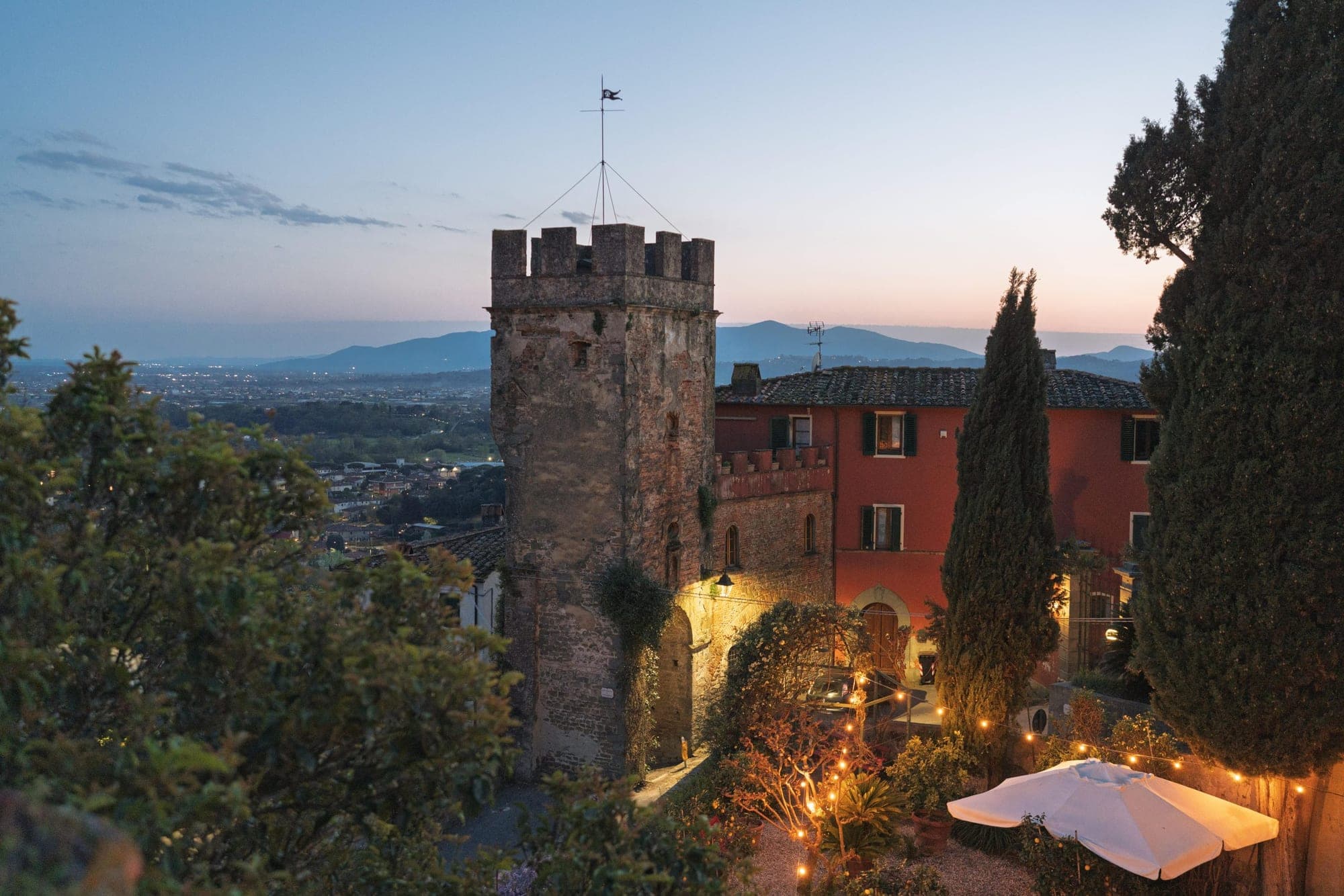Exterior of a historic building with a tower at dusk, overlooking a valley.