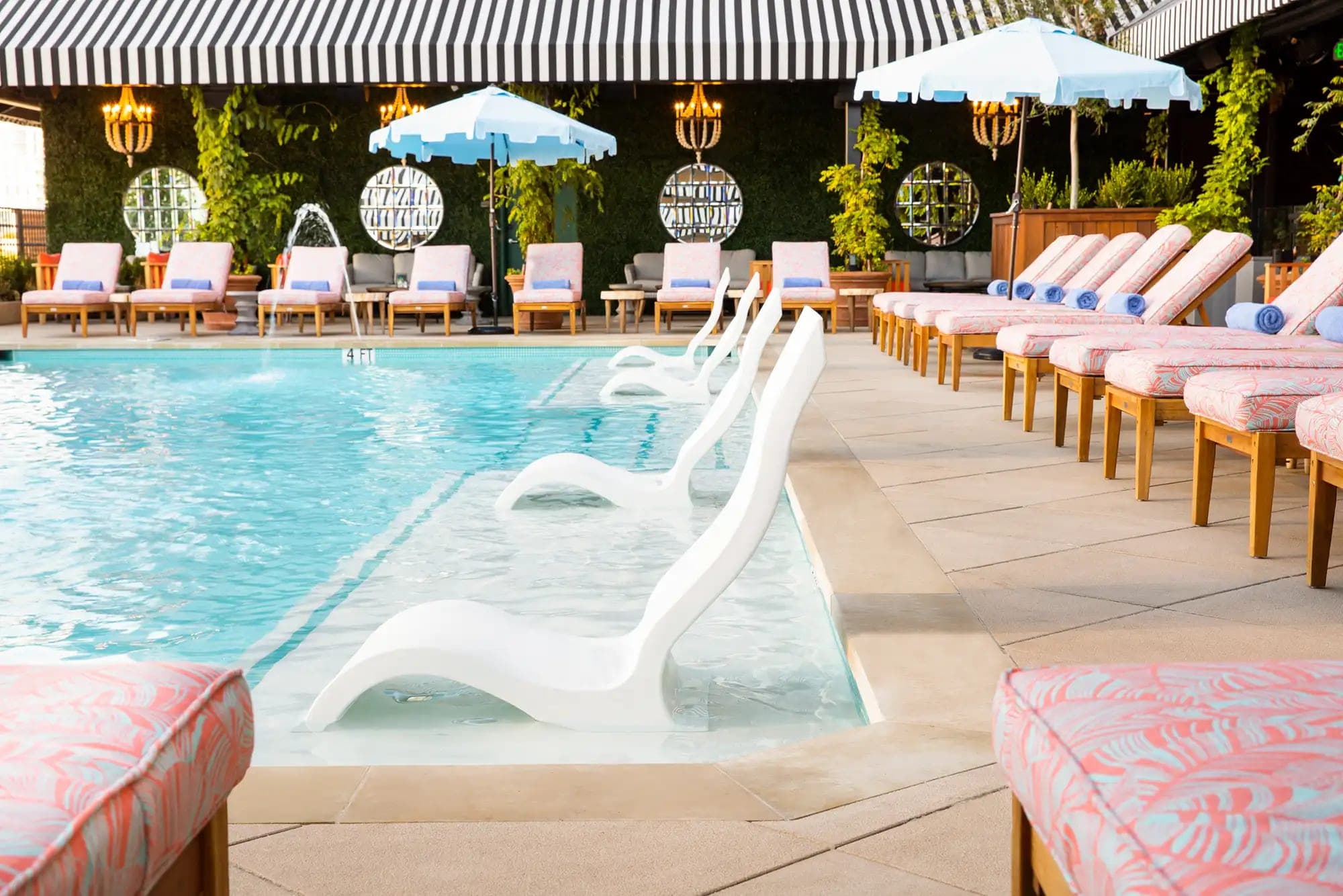A swimming pool with submerged lounge chairs and a row of lounge chairs on the deck.