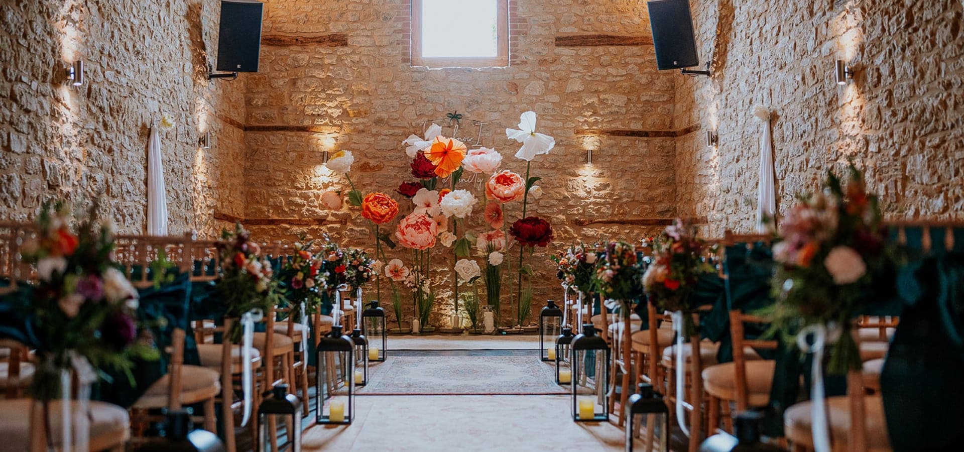 Wedding ceremony setup with floral decorations and seating in a stone building.