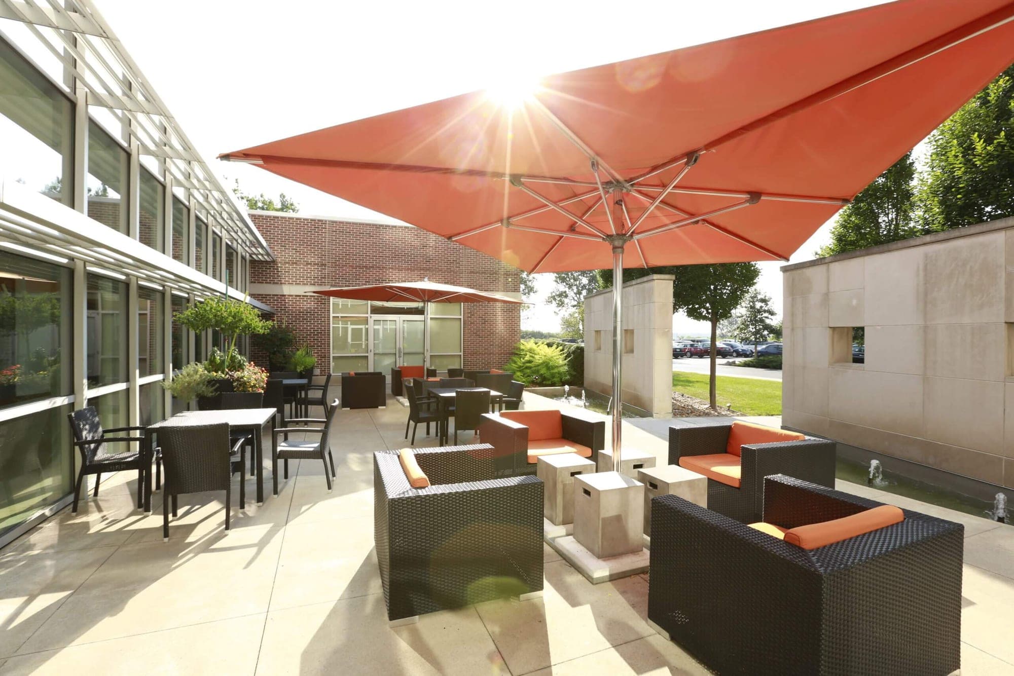 Outdoor seating area with orange umbrellas and tables on a sunny day.