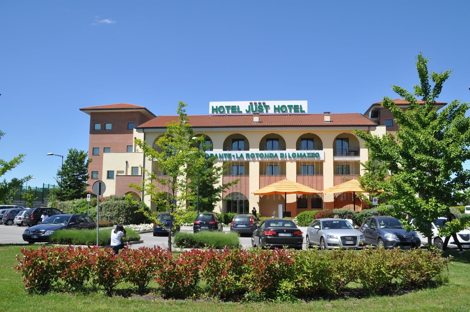 Exterior of a hotel building with a parking lot and landscaping.