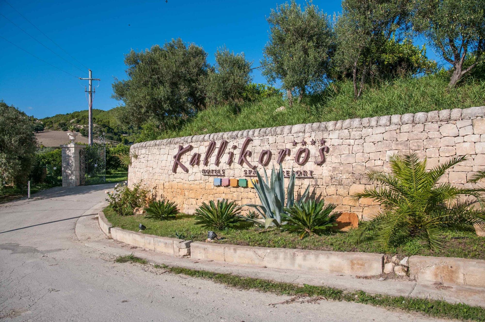 Entrance sign for Kallikoros Hotels Spa Resort on a stone wall.