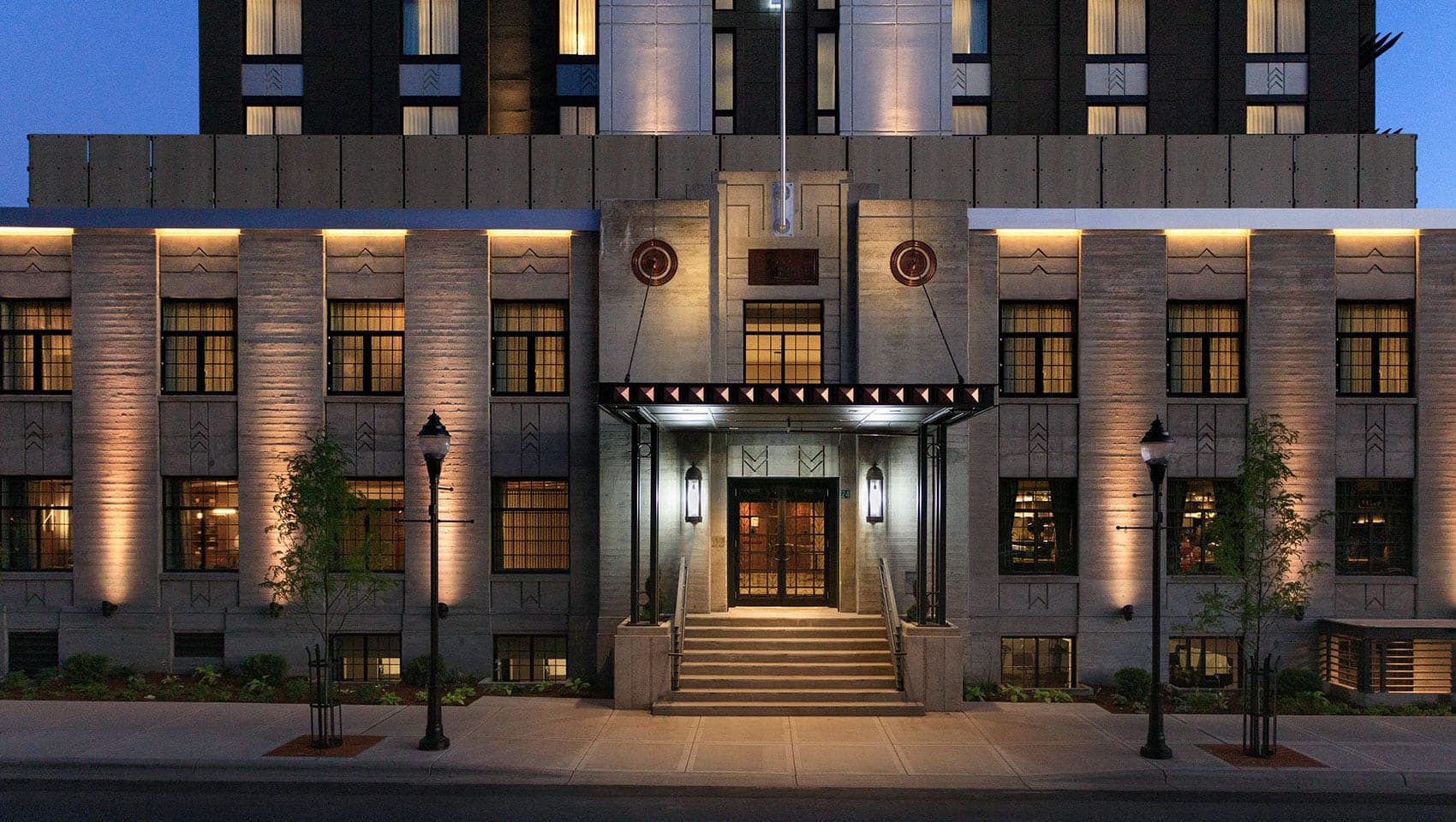 Exterior of a hotel with a grand entrance and illuminated facade at dusk.