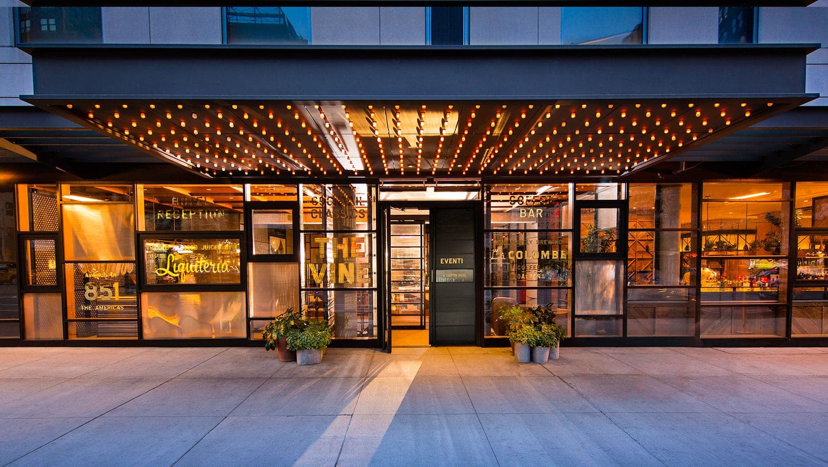 Exterior entrance of the Kimpton Hotel Eventi with illuminated signage and glass facade.