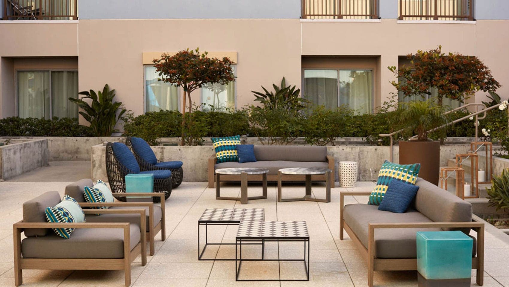 Outdoor seating area with sofas, chairs, and coffee tables on a tiled patio.