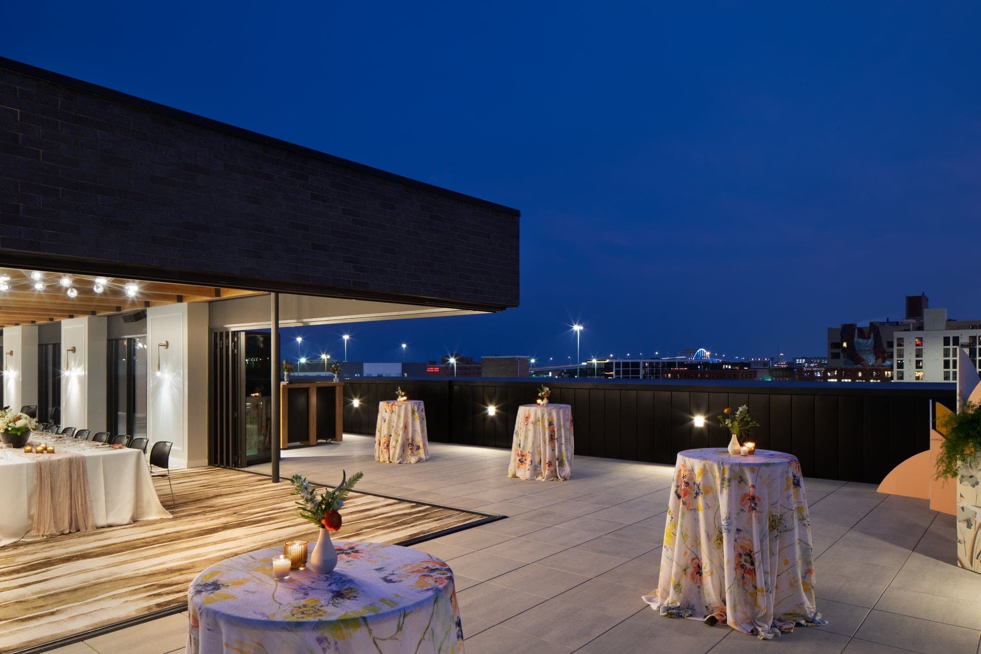Rooftop terrace with tables set for an event at dusk.