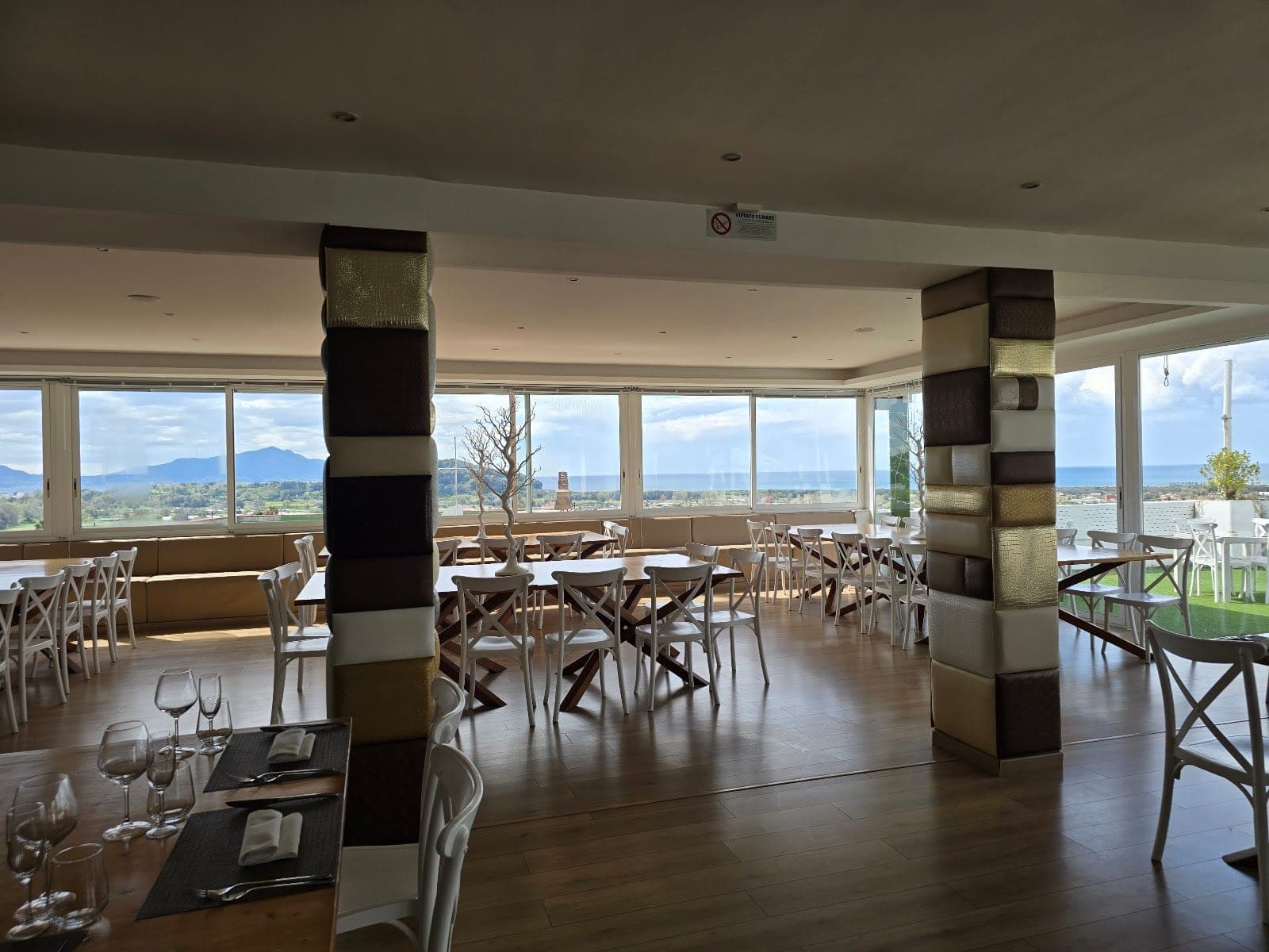 Dining room with tables set for a meal and a view of the sea.