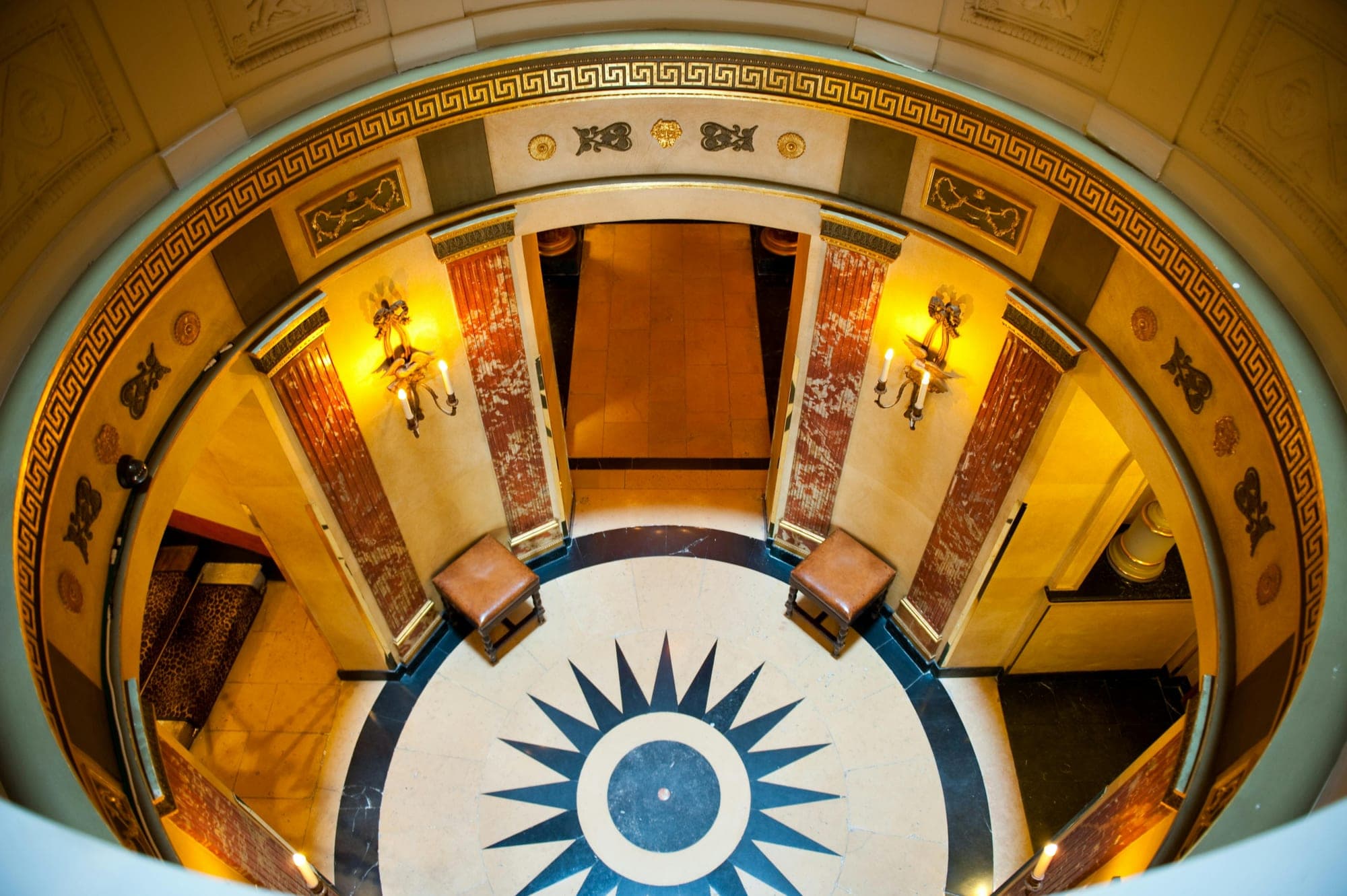 Interior view of a circular hall with a starburst floor pattern and decorative walls.