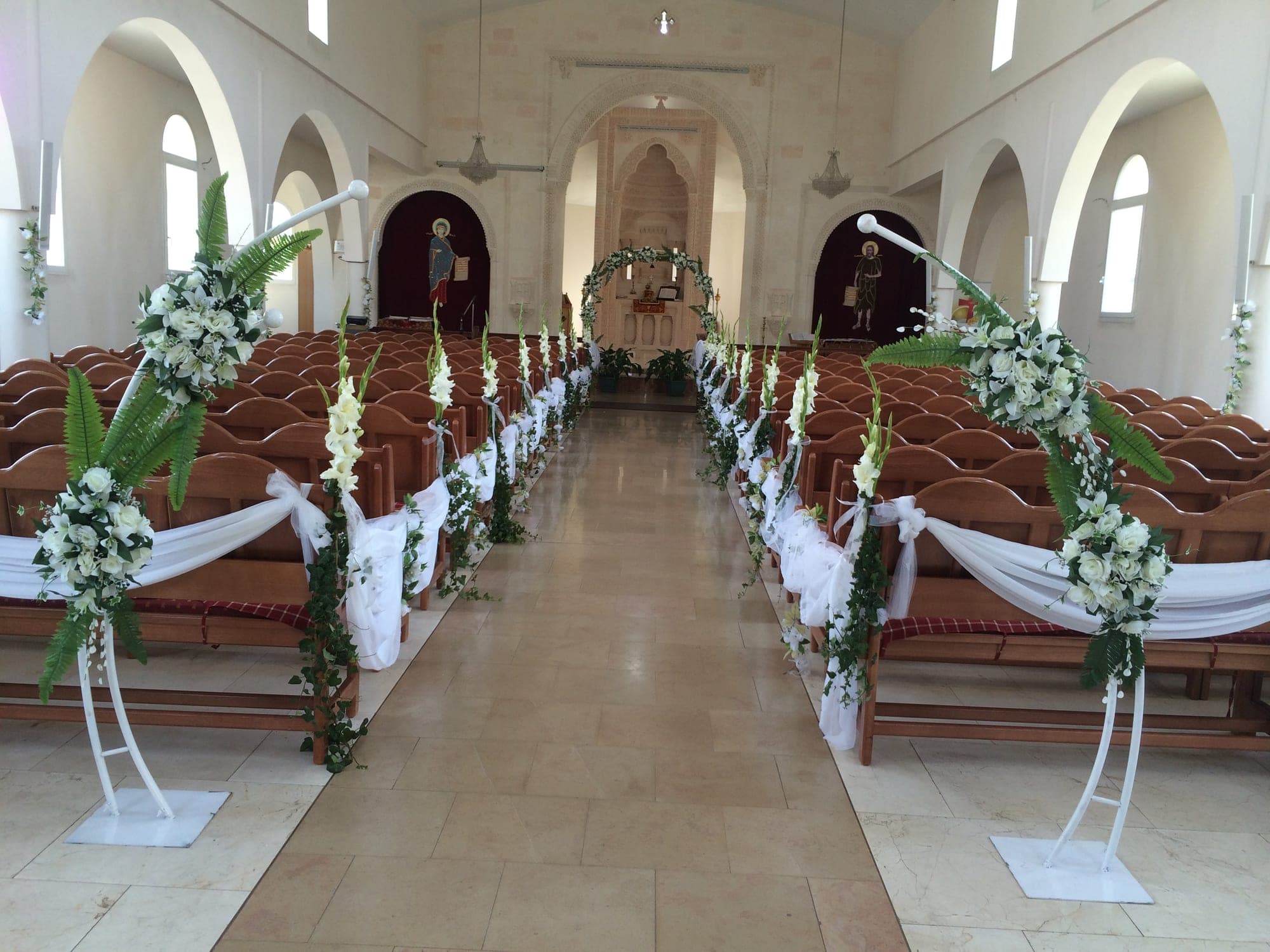 A wedding aisle decorated with white flowers and draped fabric.