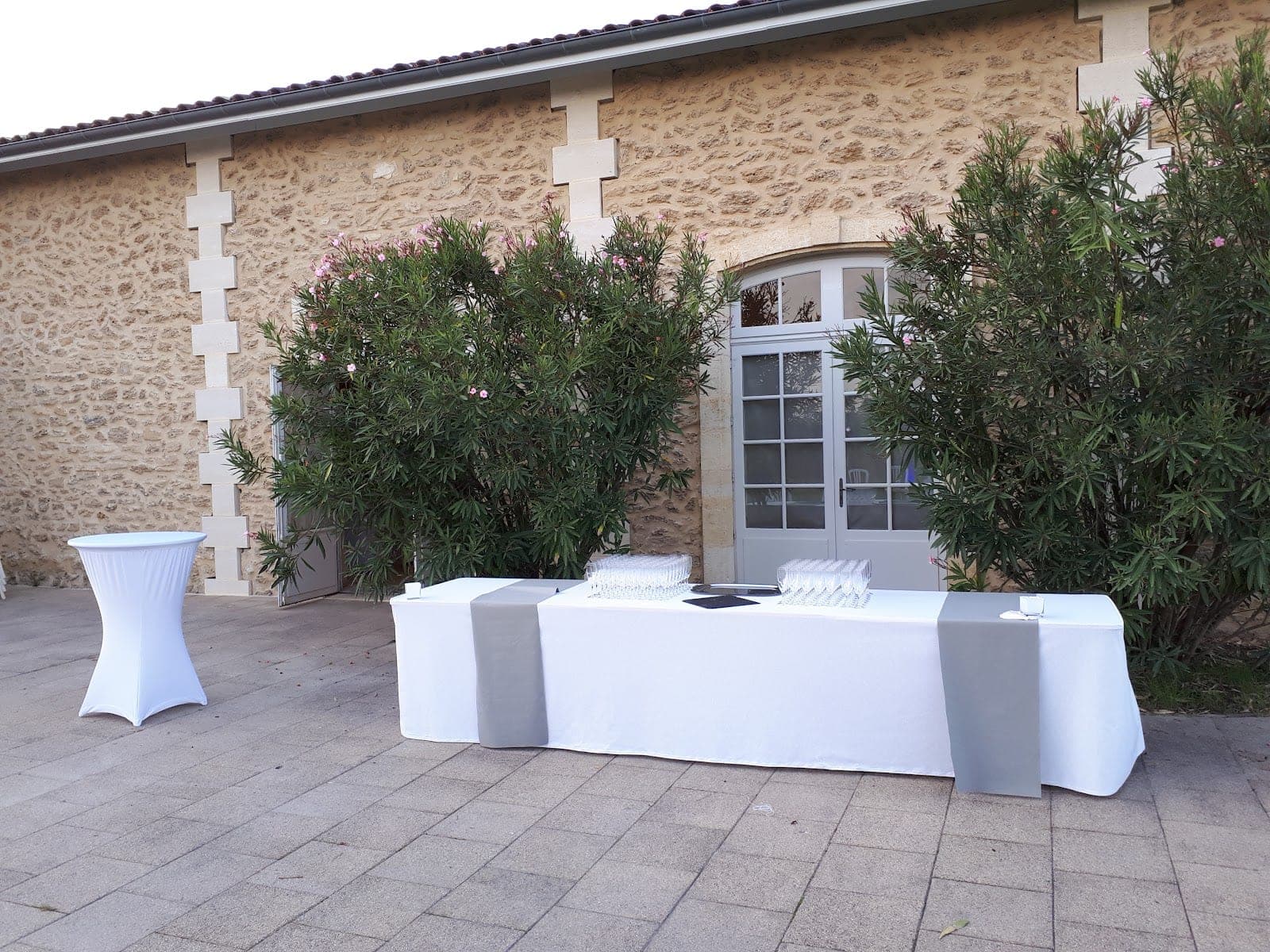 Exterior of a stone building with a door and two tables set up outside.