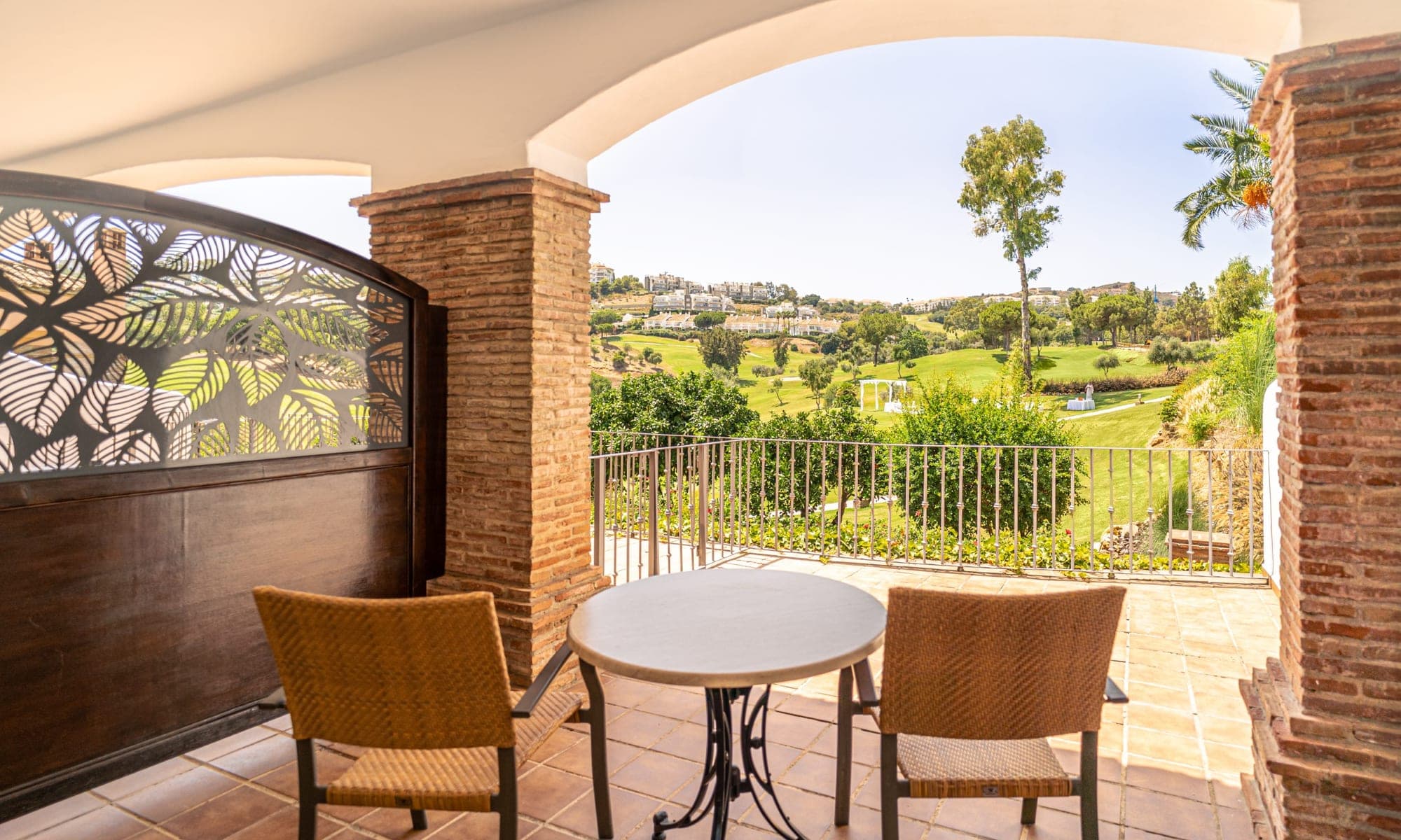 Balcony overlooking a golf course with two chairs and a table.