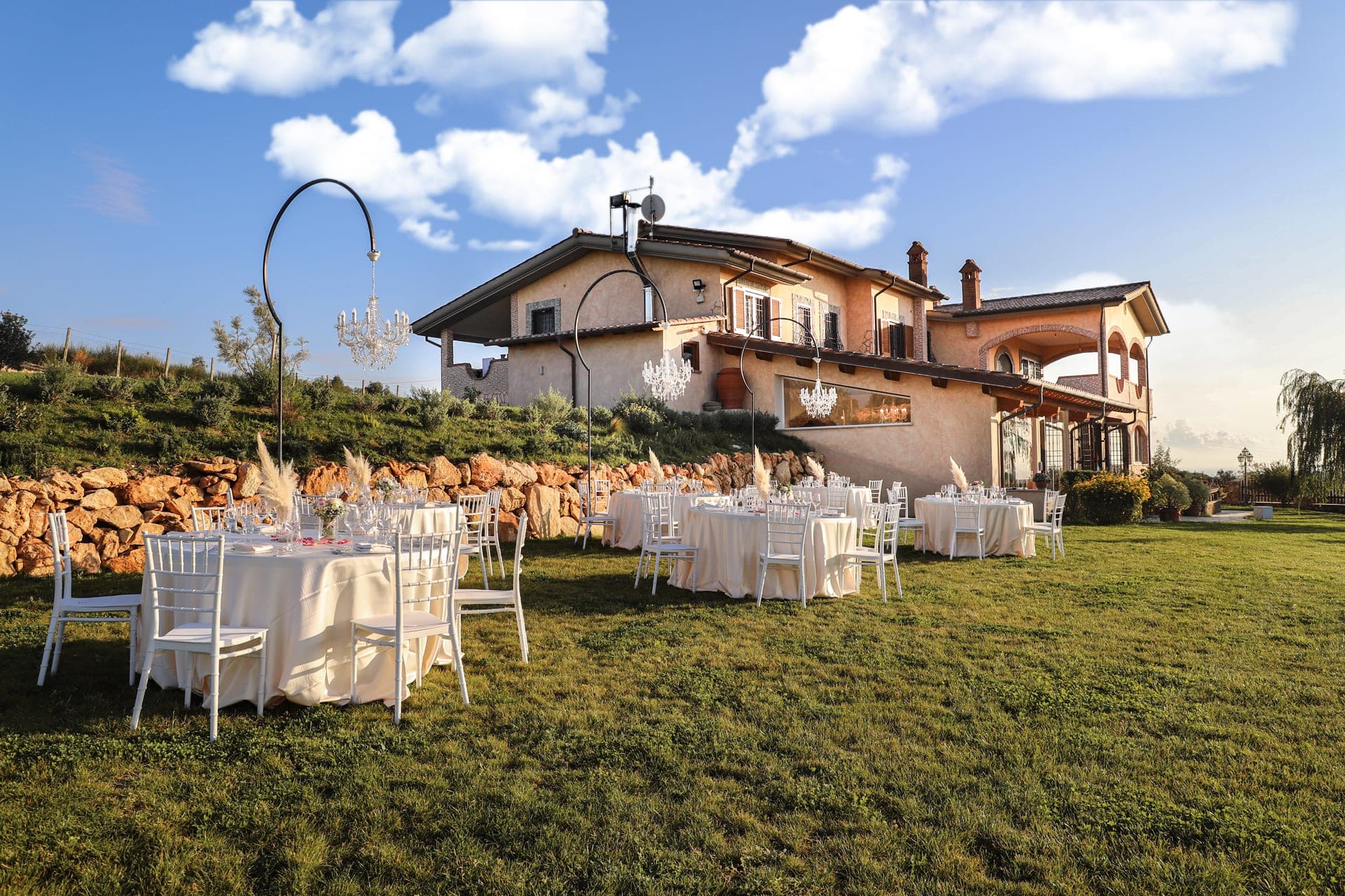 Tables set for a wedding reception on a lawn in front of a building.