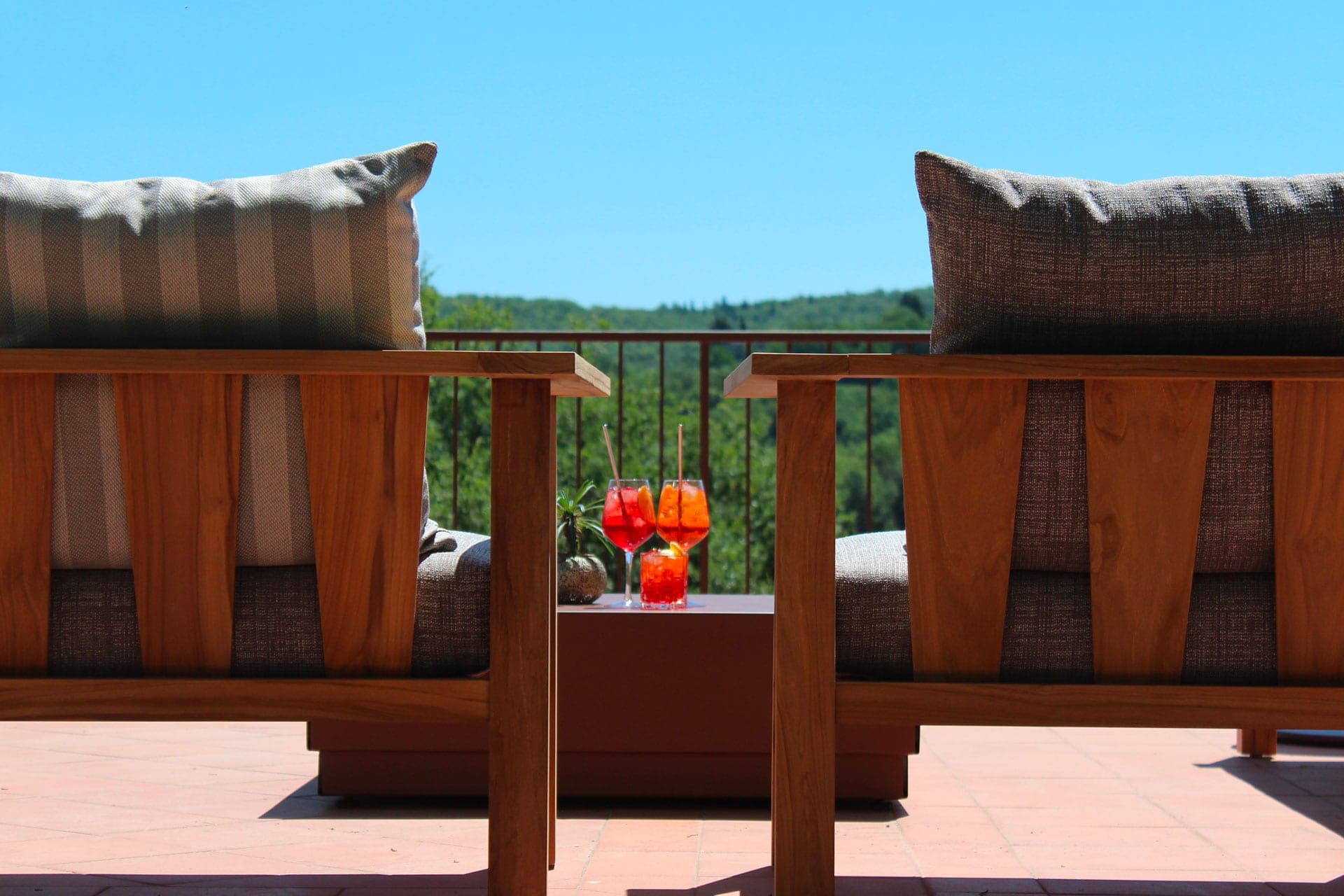 Two chairs on a terrace with drinks and a view of green hills.