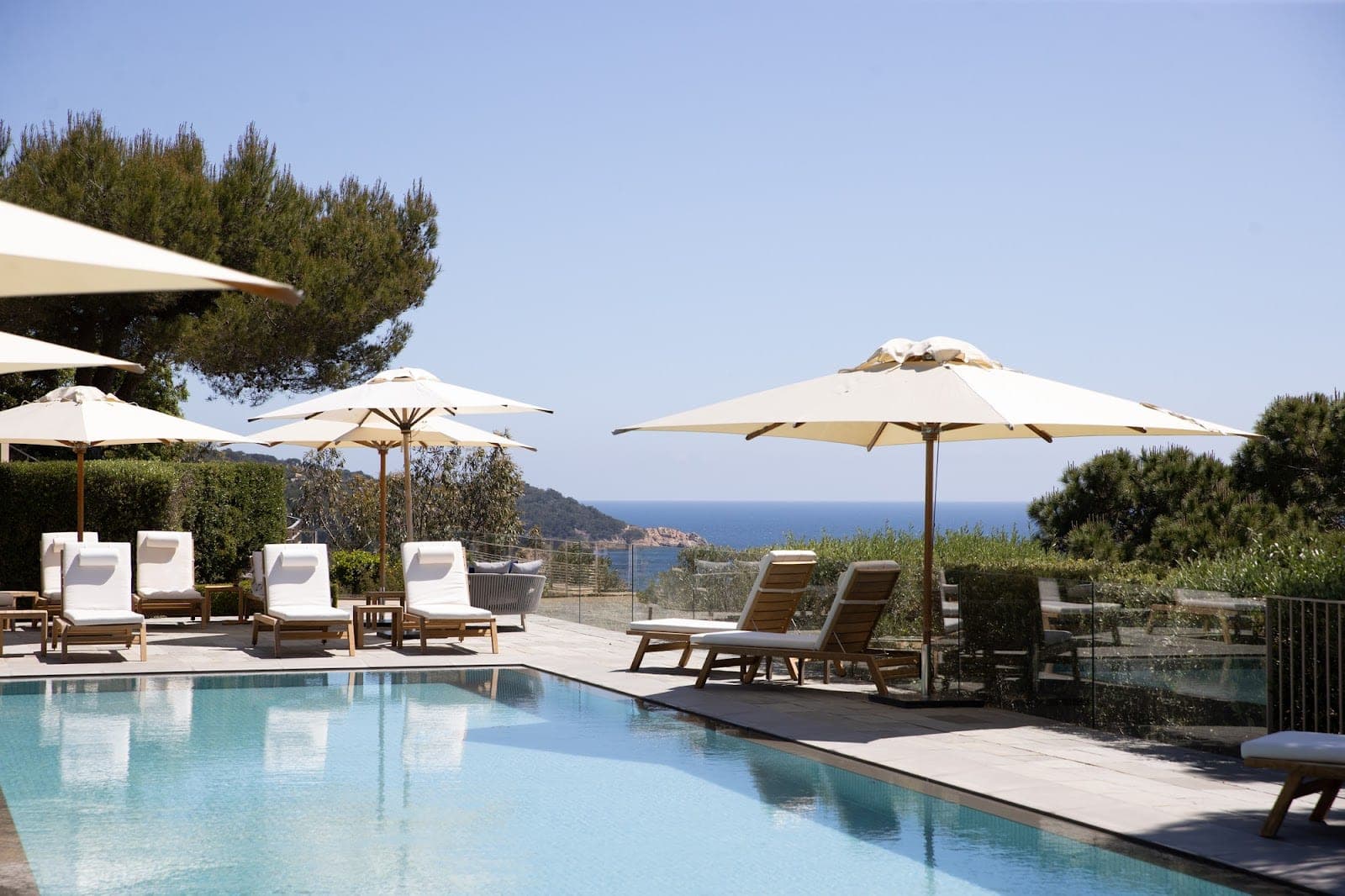 Swimming pool with lounge chairs and umbrellas overlooking the sea.
