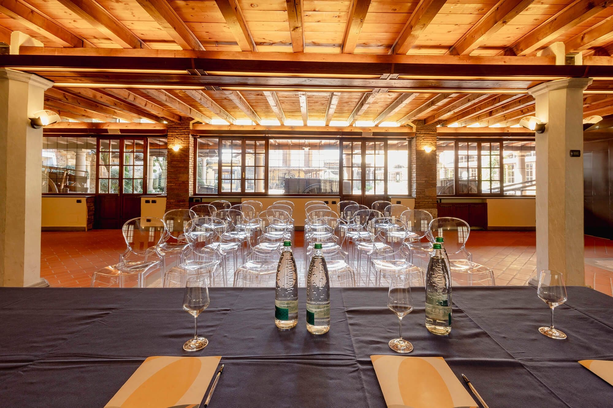 Chairs arranged in rows in a room with wooden beams and large windows.
