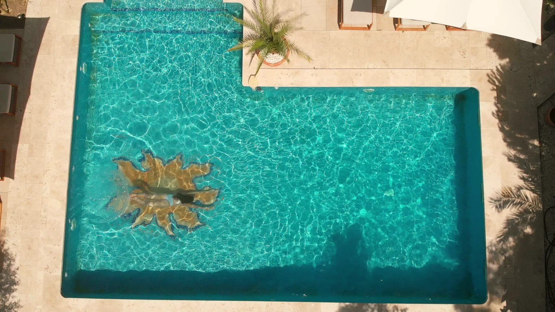 Aerial view of a swimming pool with lounge chairs and umbrellas.