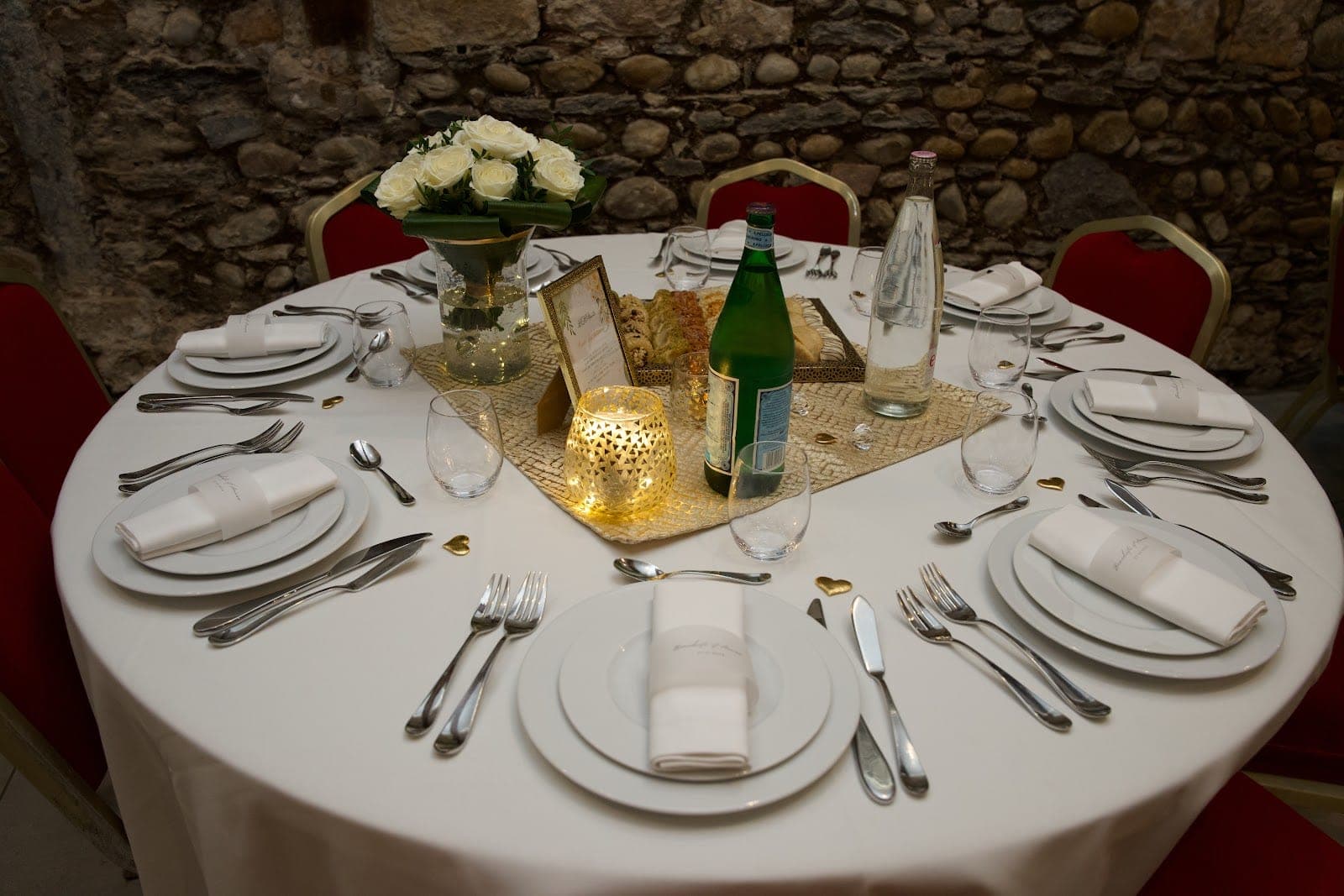 A round table set for a wedding reception with white linens and floral centerpieces.