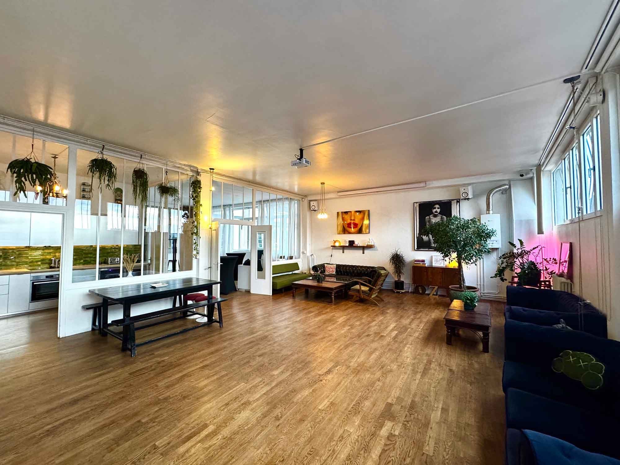 A large open-plan room with a dining table, lounge area, and kitchen.